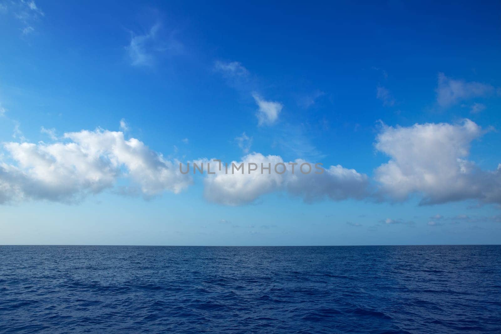 cumulus clouds in blue sky over ocean water horizon