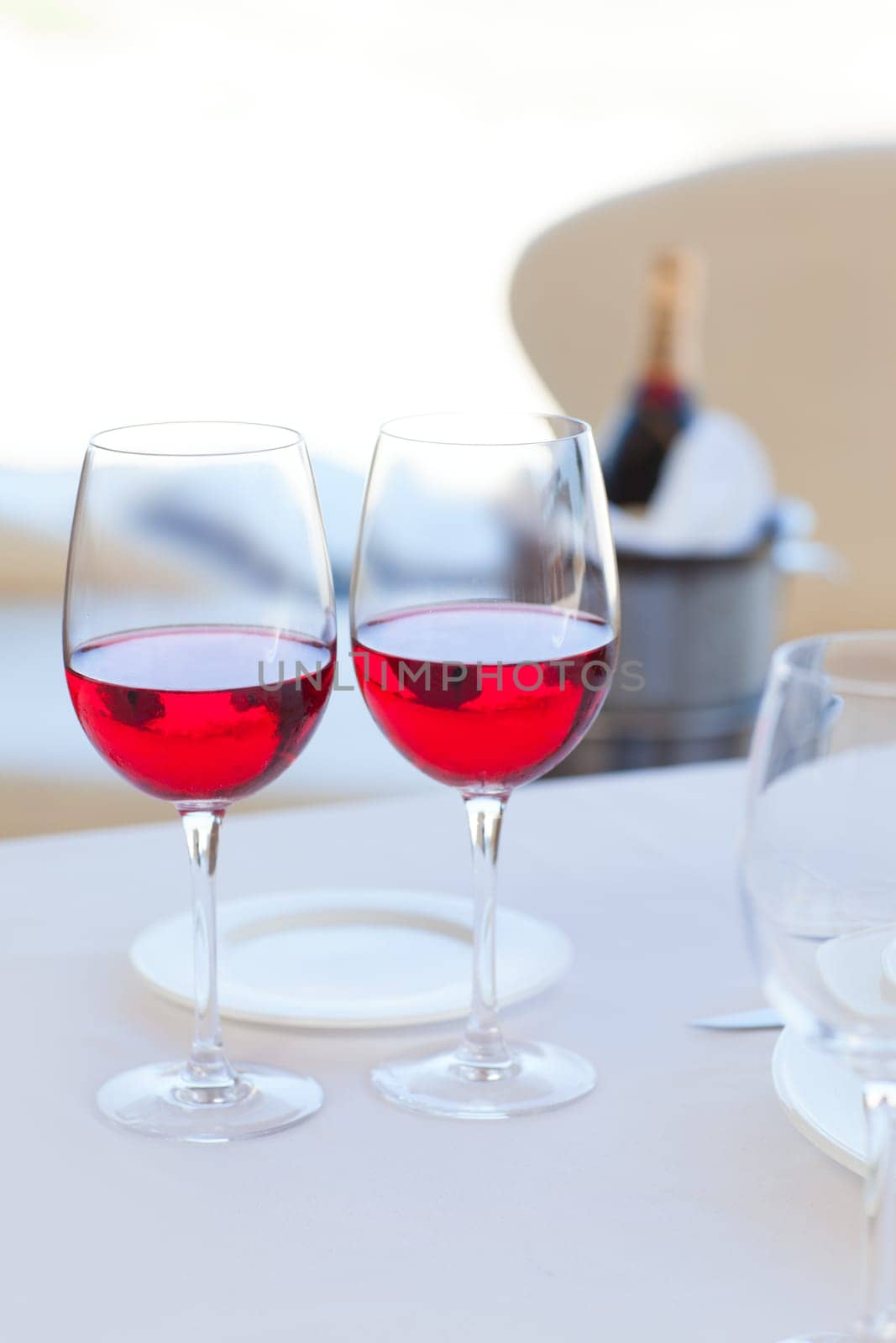 two cups of red wine and bottle in background on ice bucket