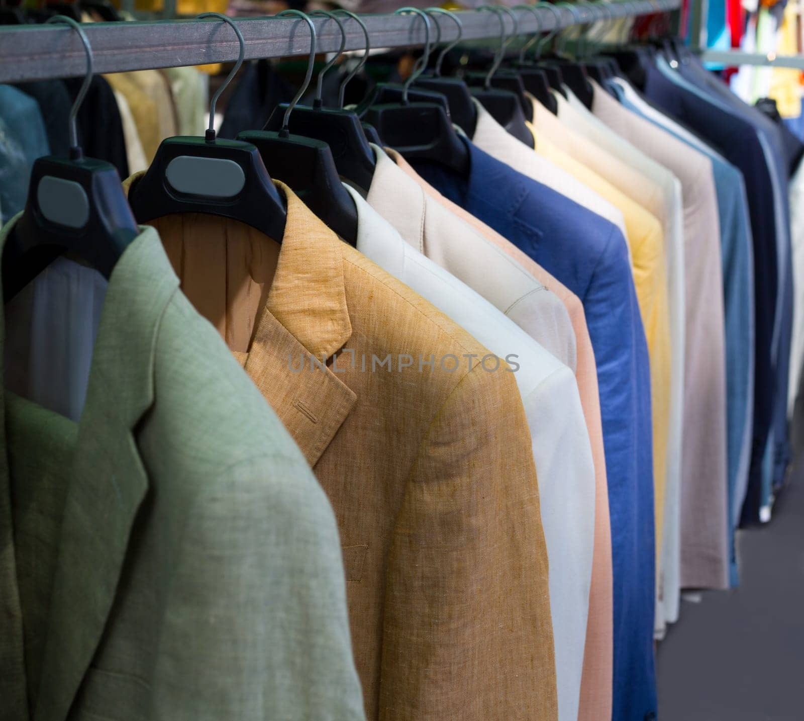 colorful male suits in row in a hanger as a pattern