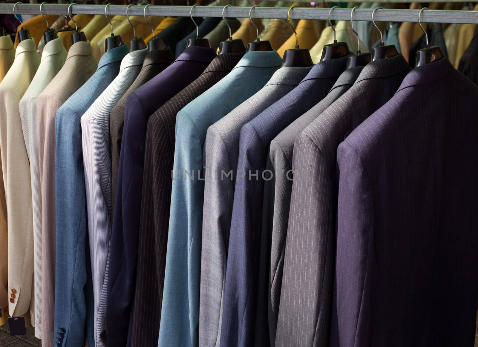 colorful male suits in row in a hanger as a pattern