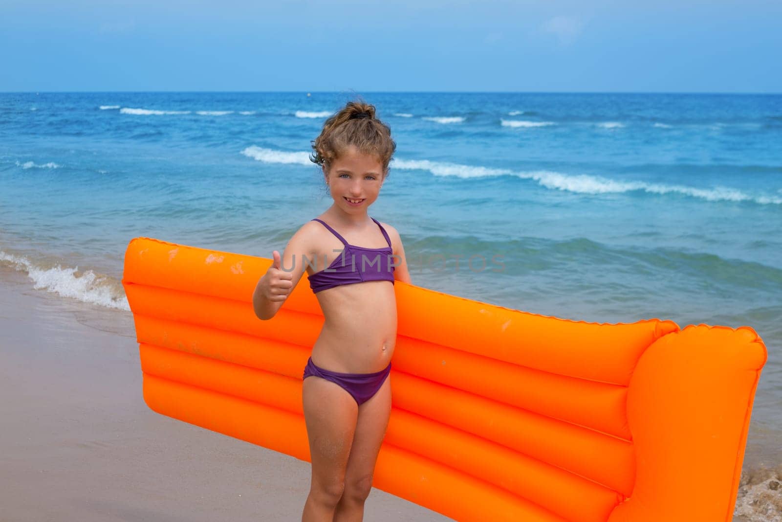 children kid girl standing in beach shore with orange floating lounge ok hand sign