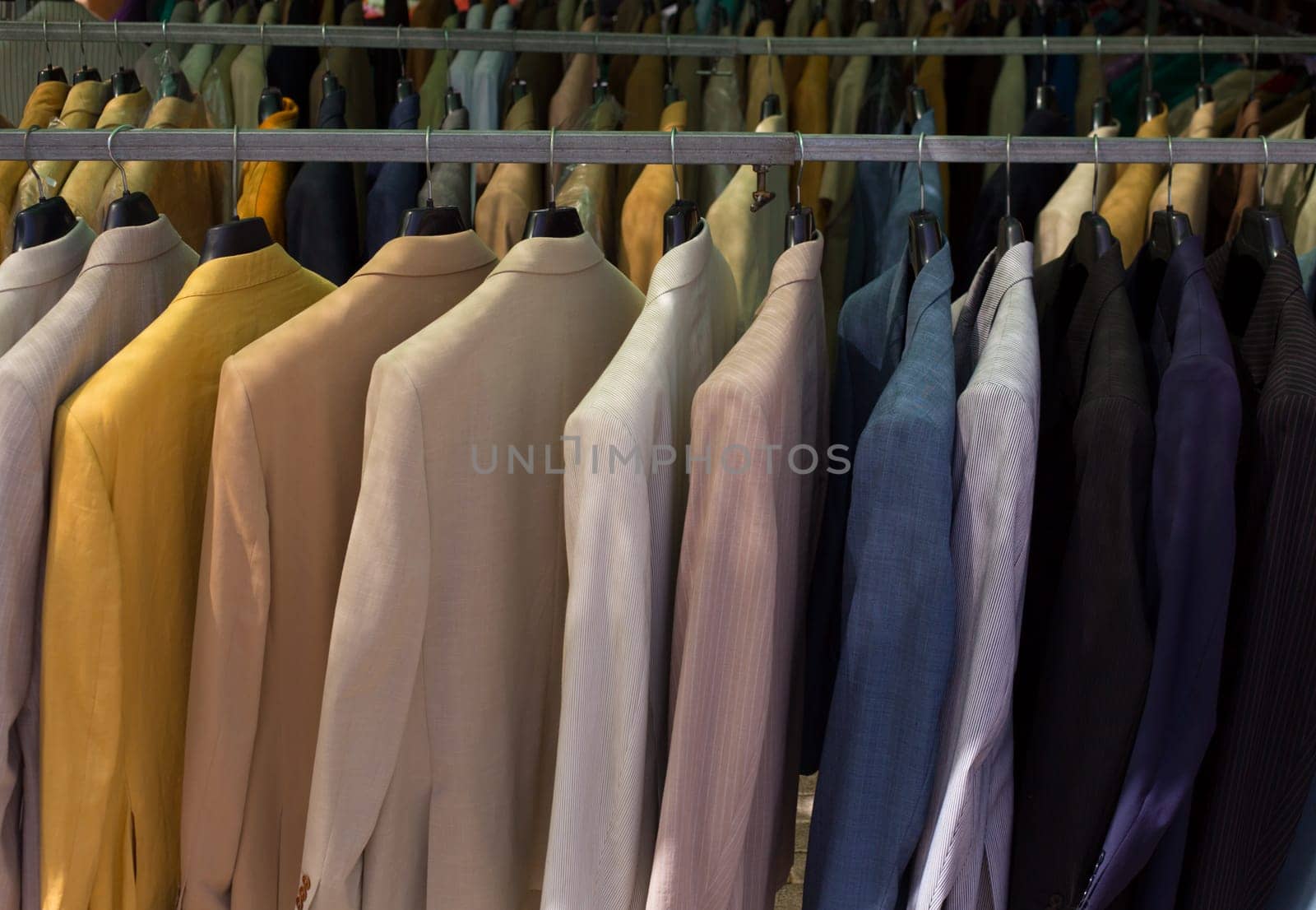 colorful male suits in row in a hanger as a pattern