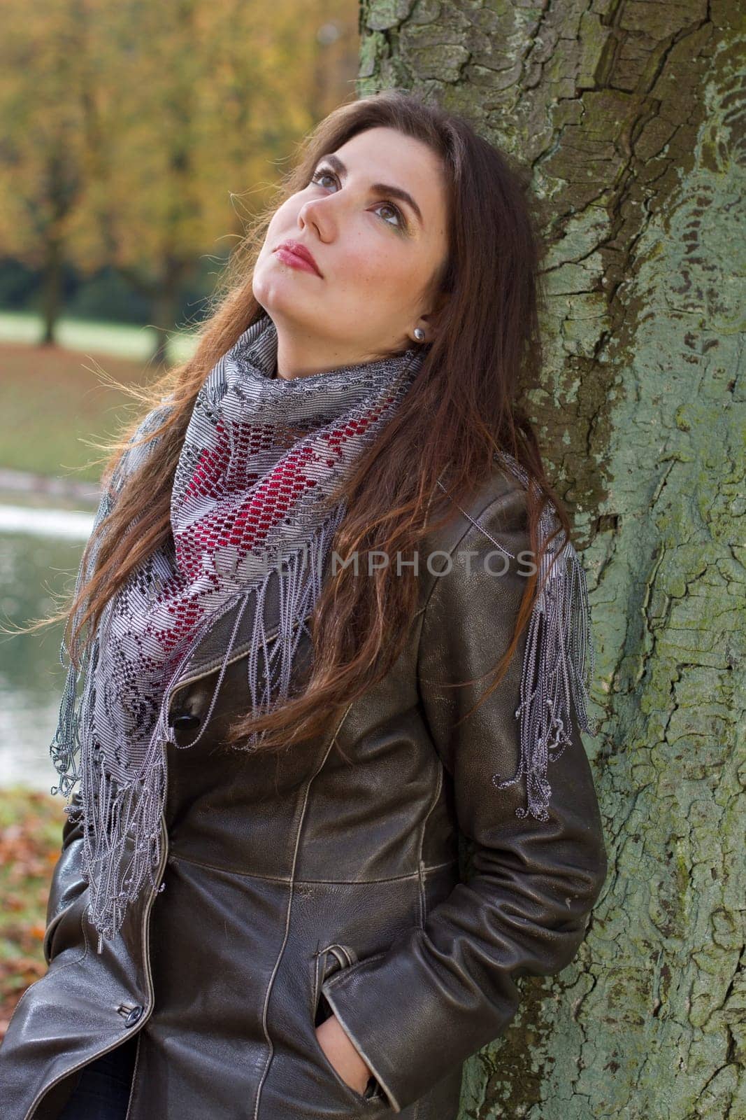 sad woman in park standing at the tree