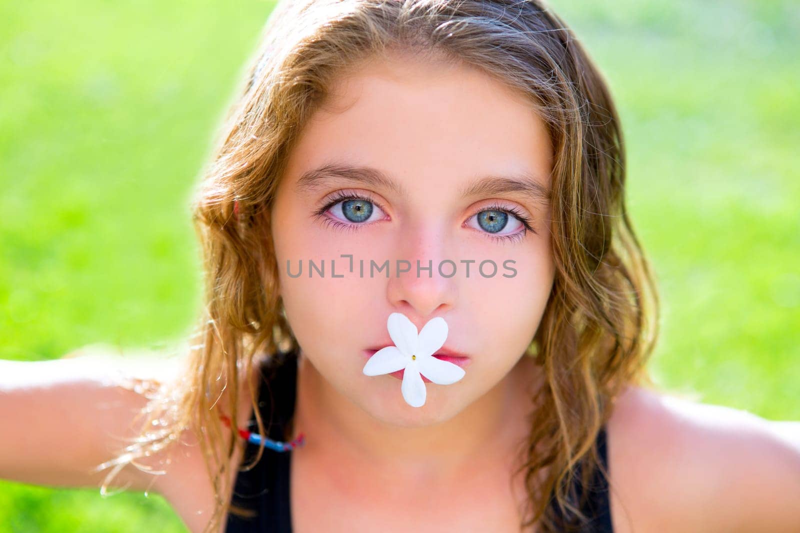 blue eyes children girl with jasmine flower in mouth at garden grass