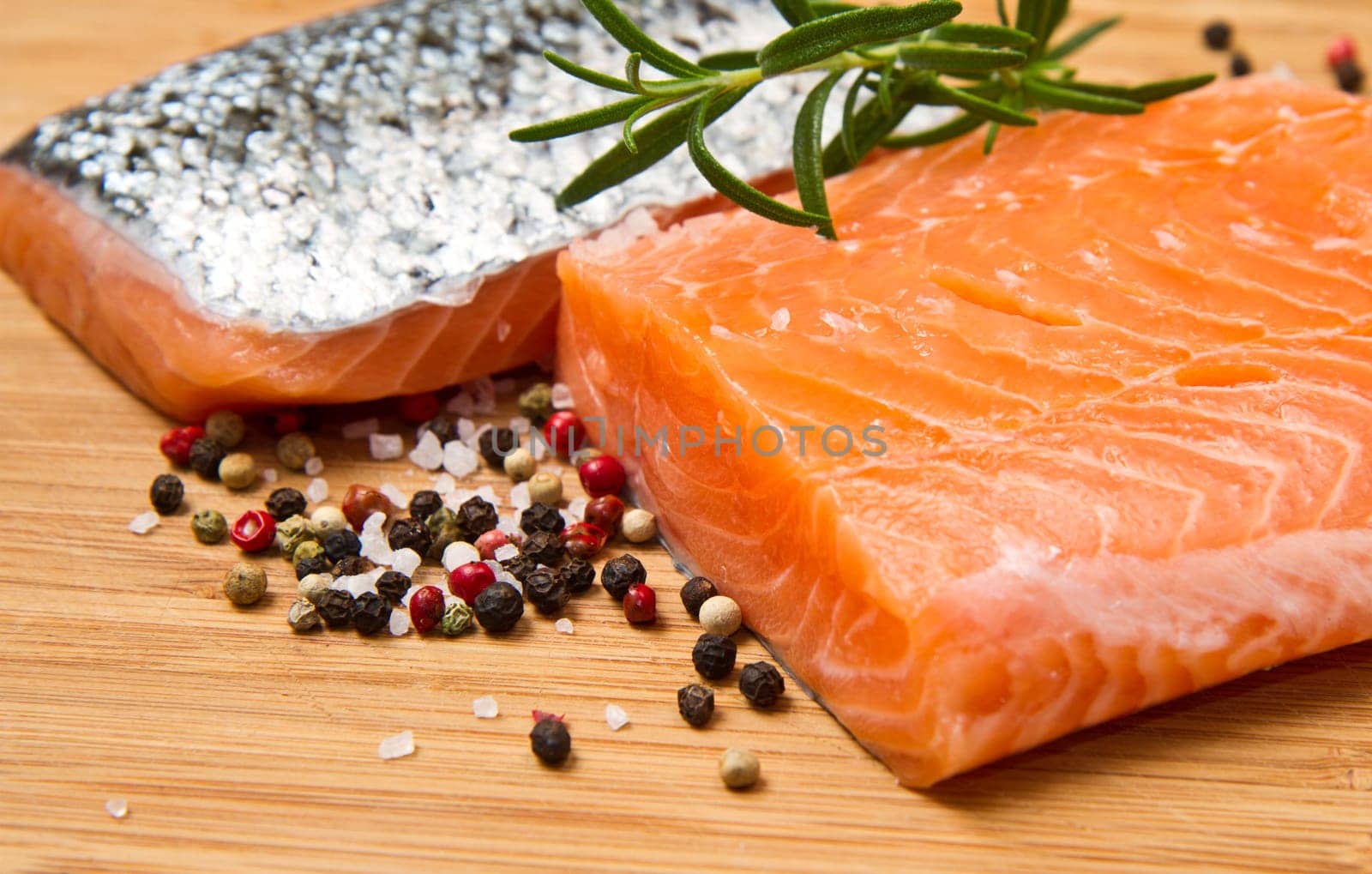 Fresh salmon fillet on wooden board with pepper and rosemary