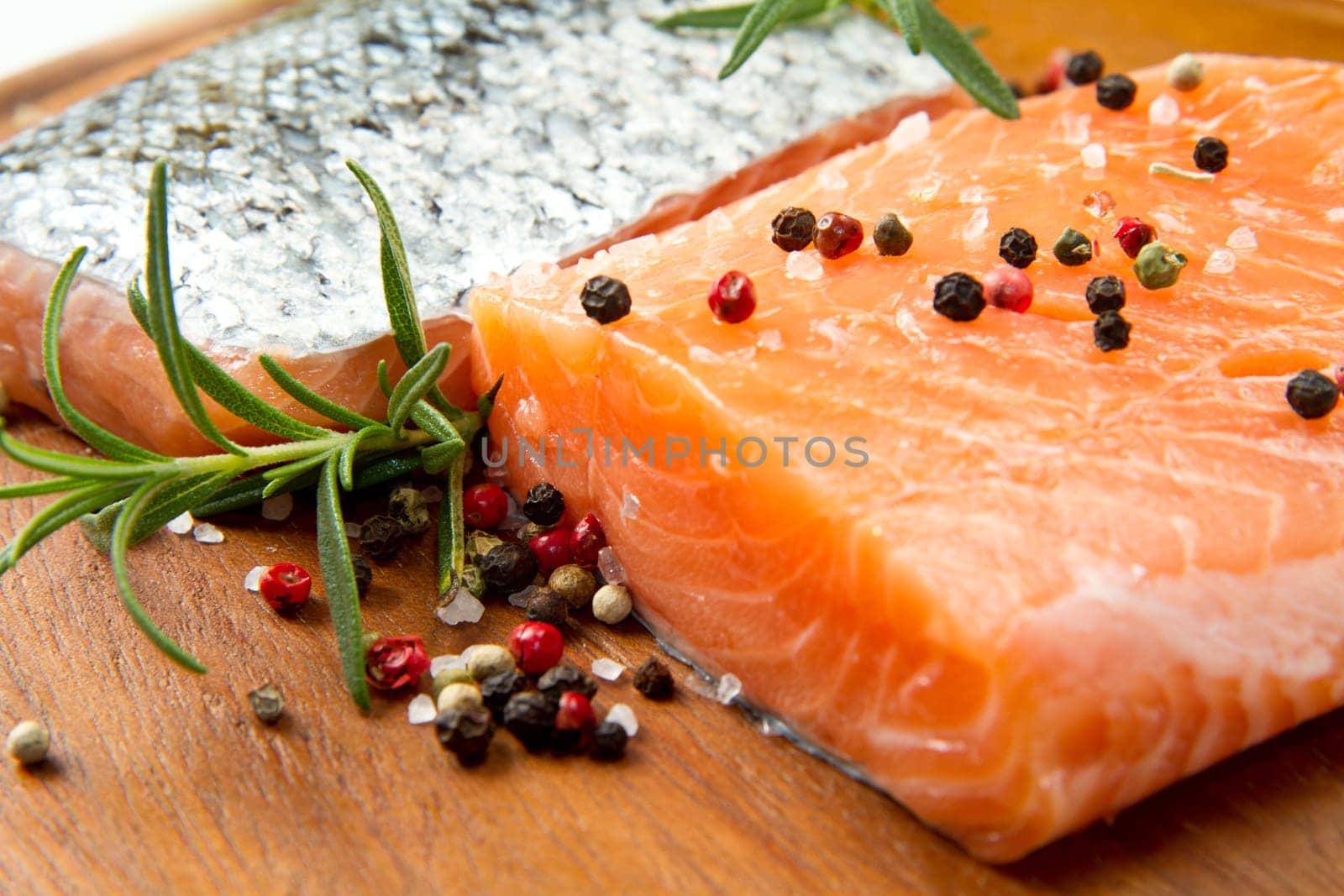 Fresh salmon fillet on wooden board with pepper and rosemary