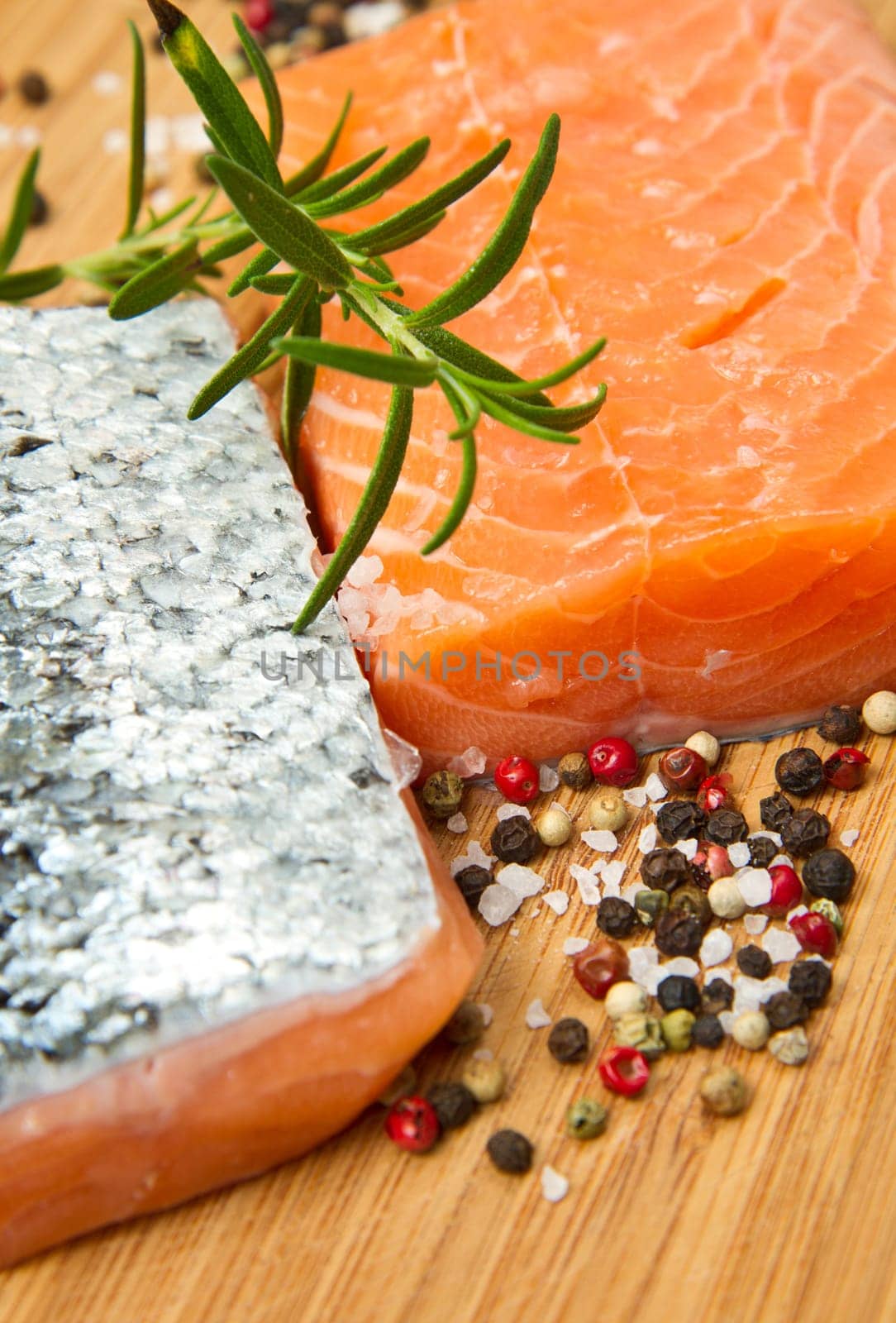 Fresh salmon fillet on wooden board with pepper and rosemary