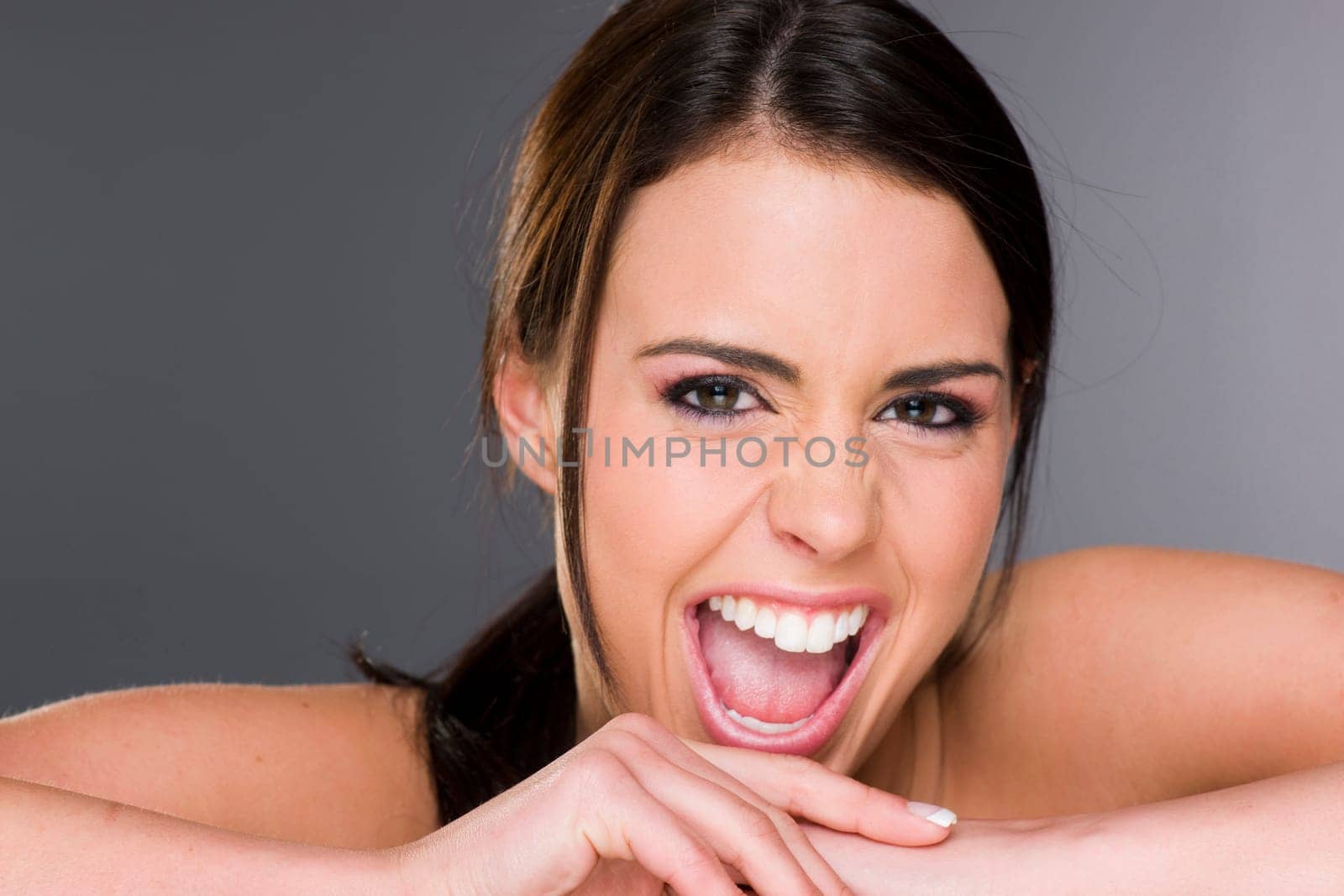 Stunningly beautiful young woman in a head and shoulders pose laughs loudly