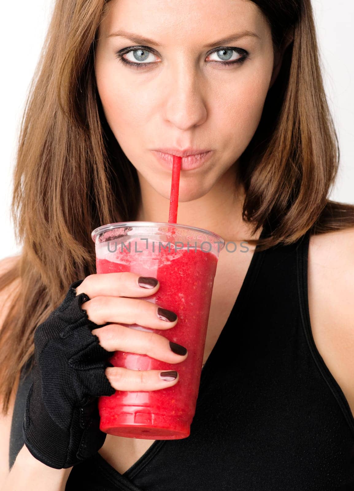 Attractive woman sips a red fruit smoothie through a straw