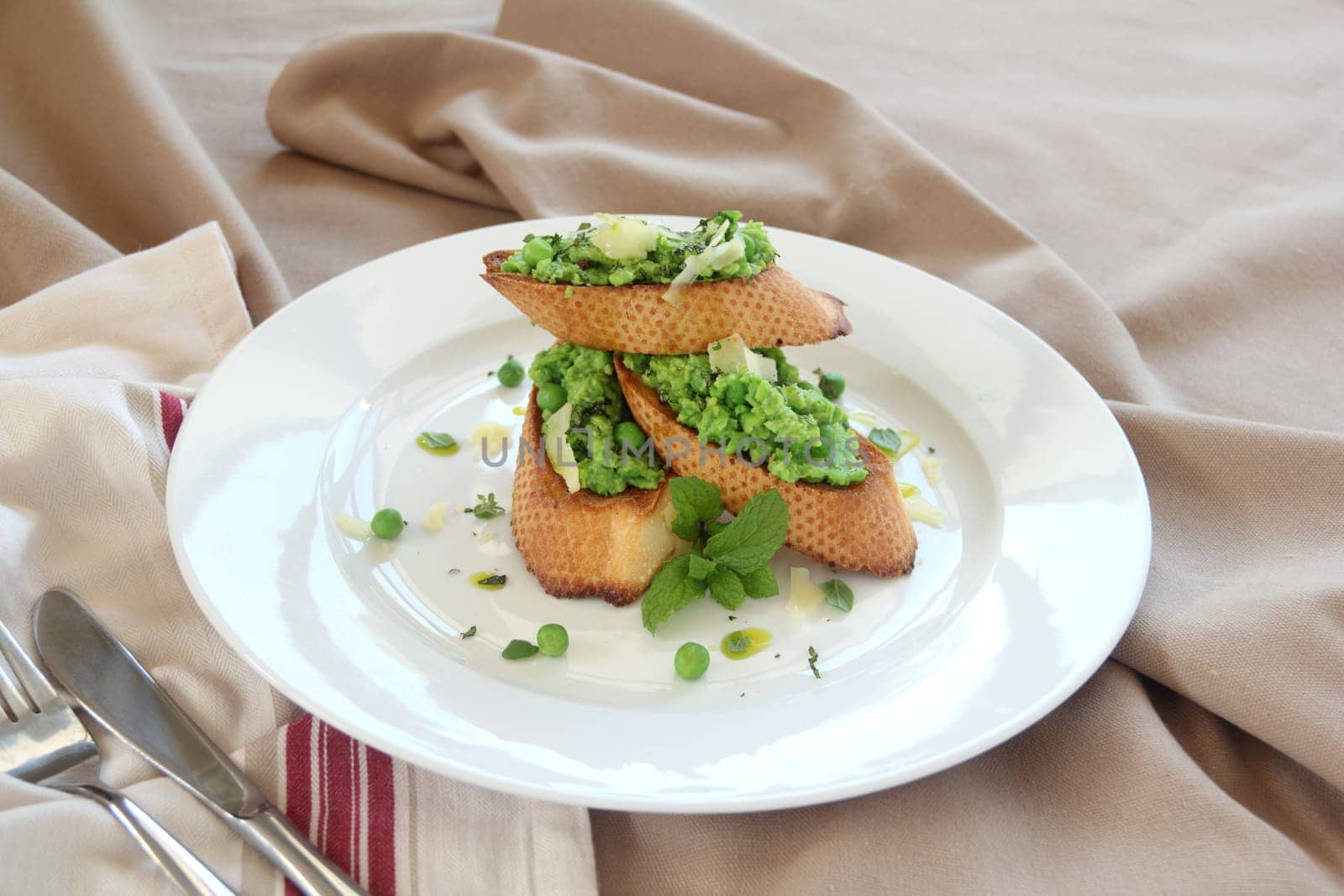 Delicious green pea baguettes with shaved cheese and mint with avocado oil.