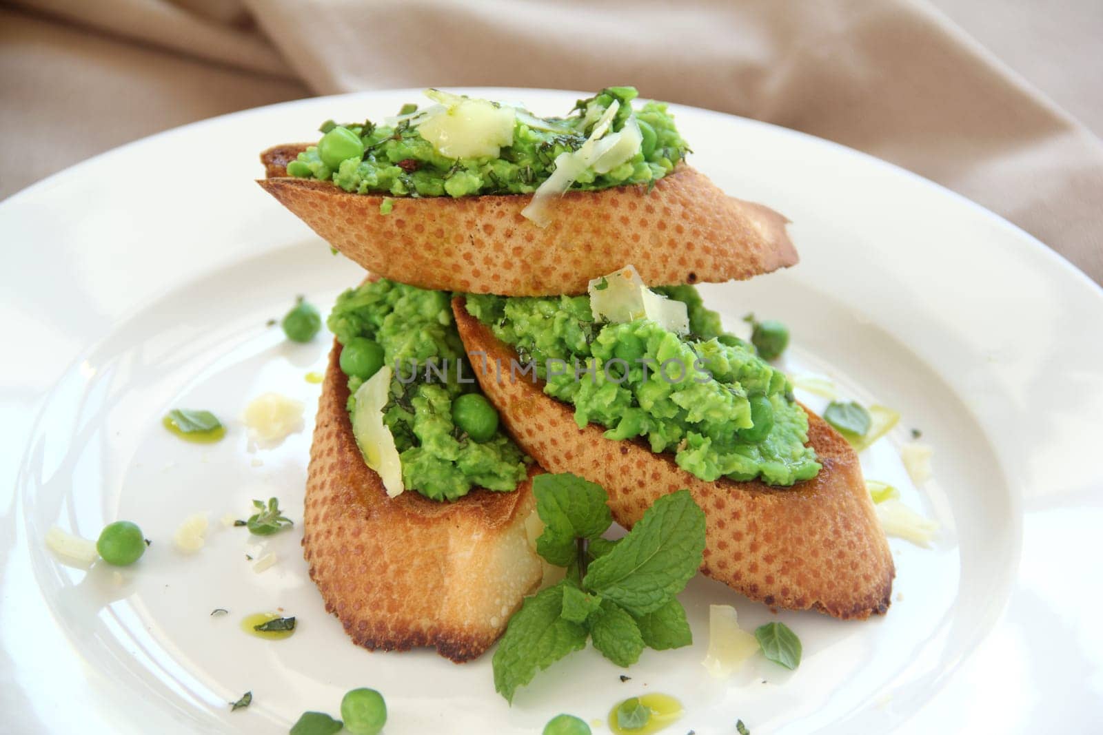 Delicious green pea baguettes with shaved cheese and mint with avocado oil.
