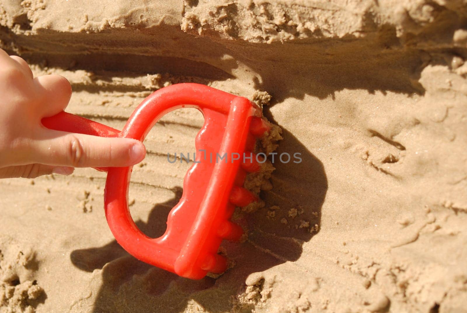 Summer concept: Kid hand playing with a toy at the beach.
