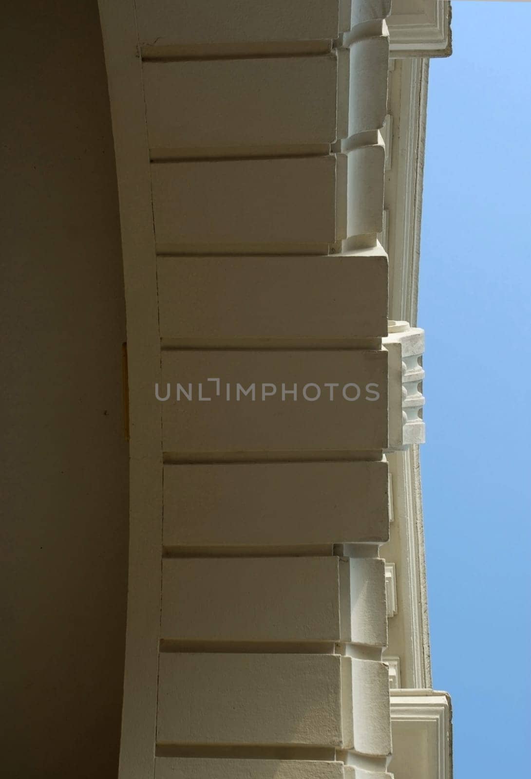 Architectural detail of an antique building on a blue sky background. Bottom View
