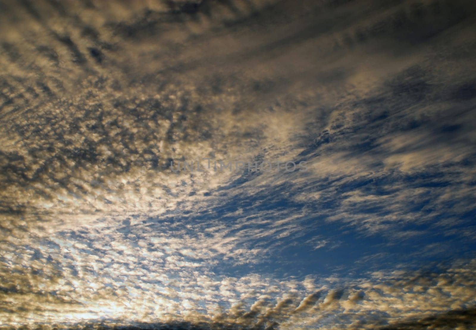 Sun light passes through dramatic cirrus clouds. Sunrise sky background.