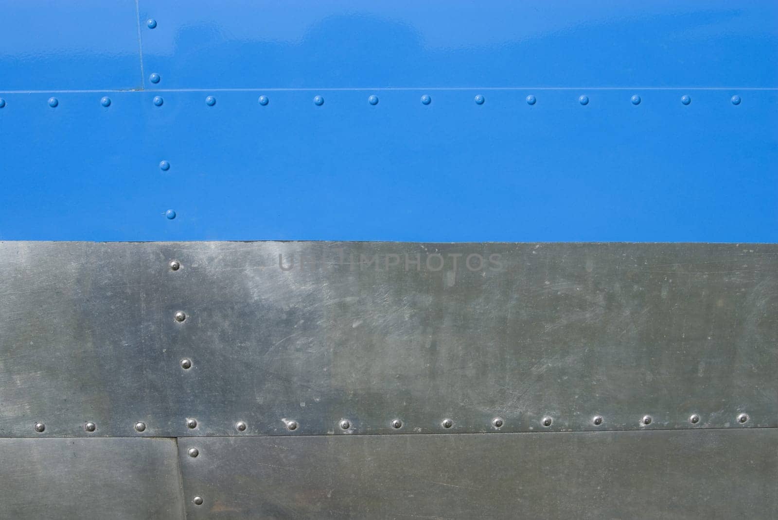 Airplane fuselage blue and silvel metal texture with rivets. Useful as background for design works.