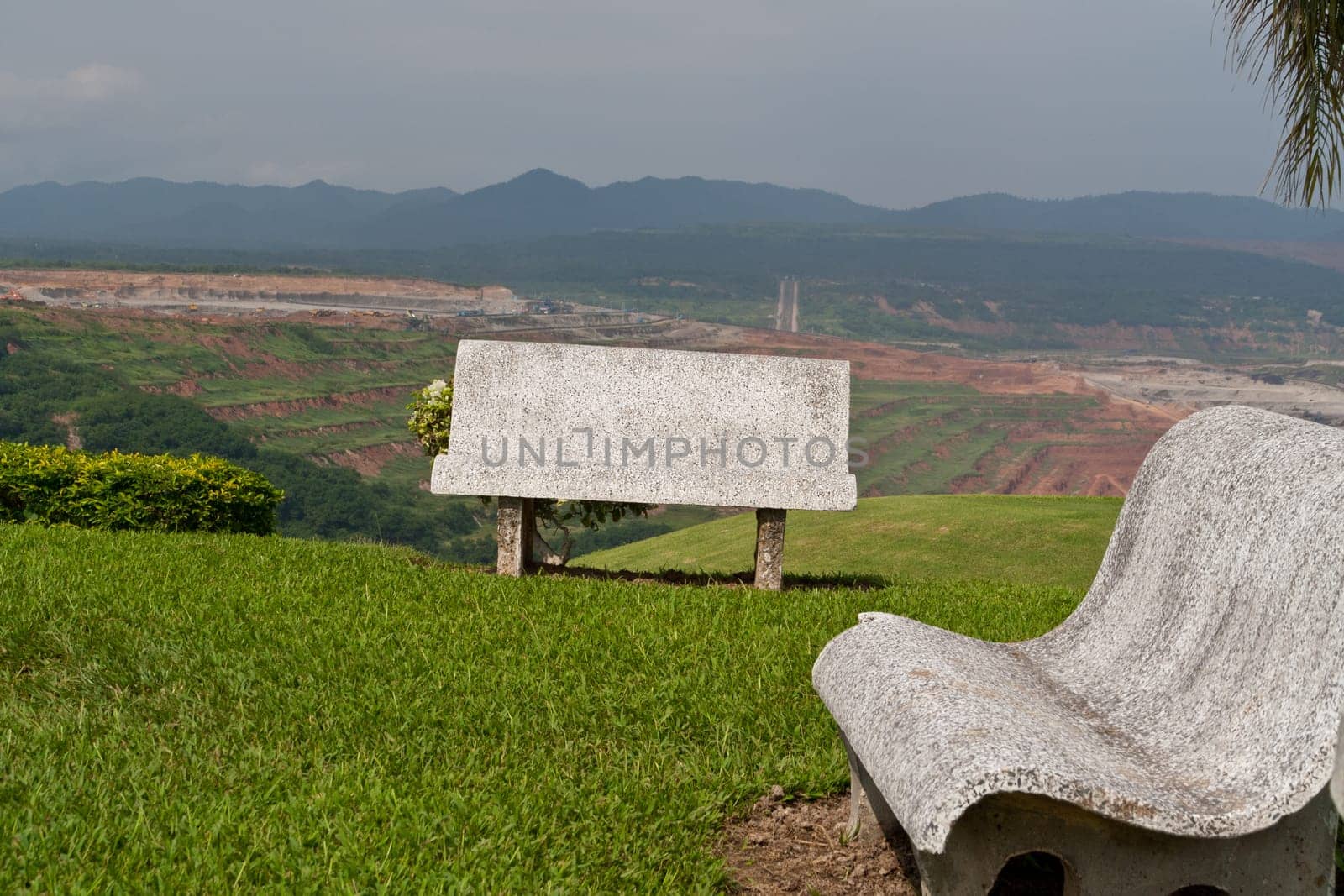 Cement bench on green grass and sky background