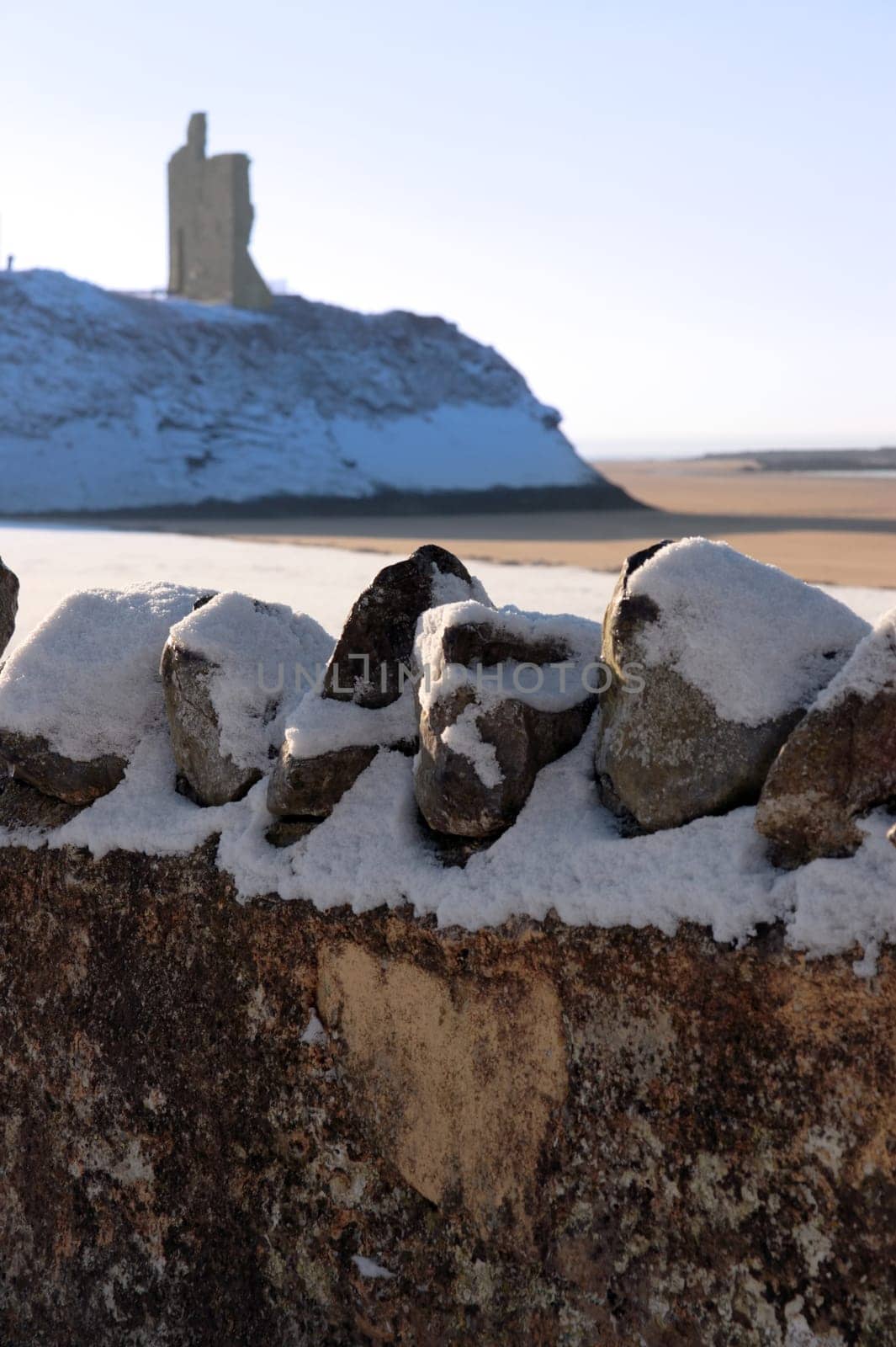 a seasonal snow covered stone wall view of castle and atlantic ocean in ireland