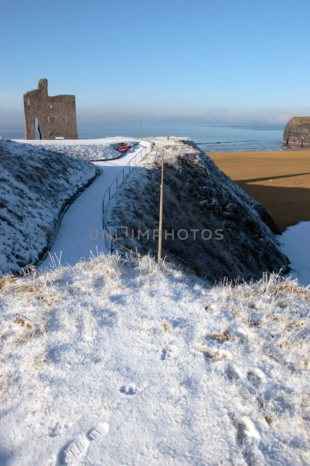 a seasonal snow covered view of atlantic ocean and ballybunion castle beach and cliffs on a frosty snow covered winters day