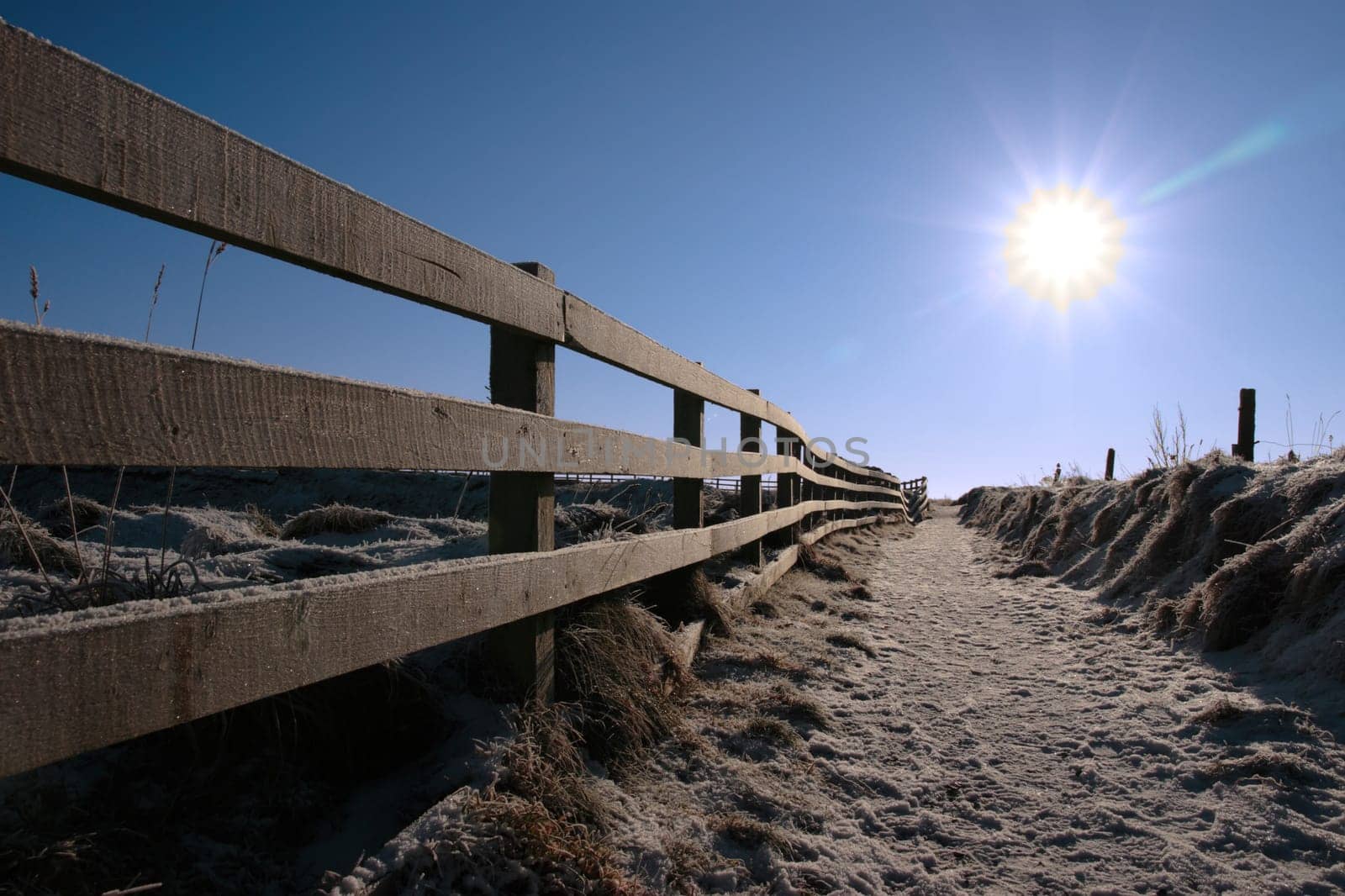 frosty winters view at ballybunion cliffside walk with bright sun and fence