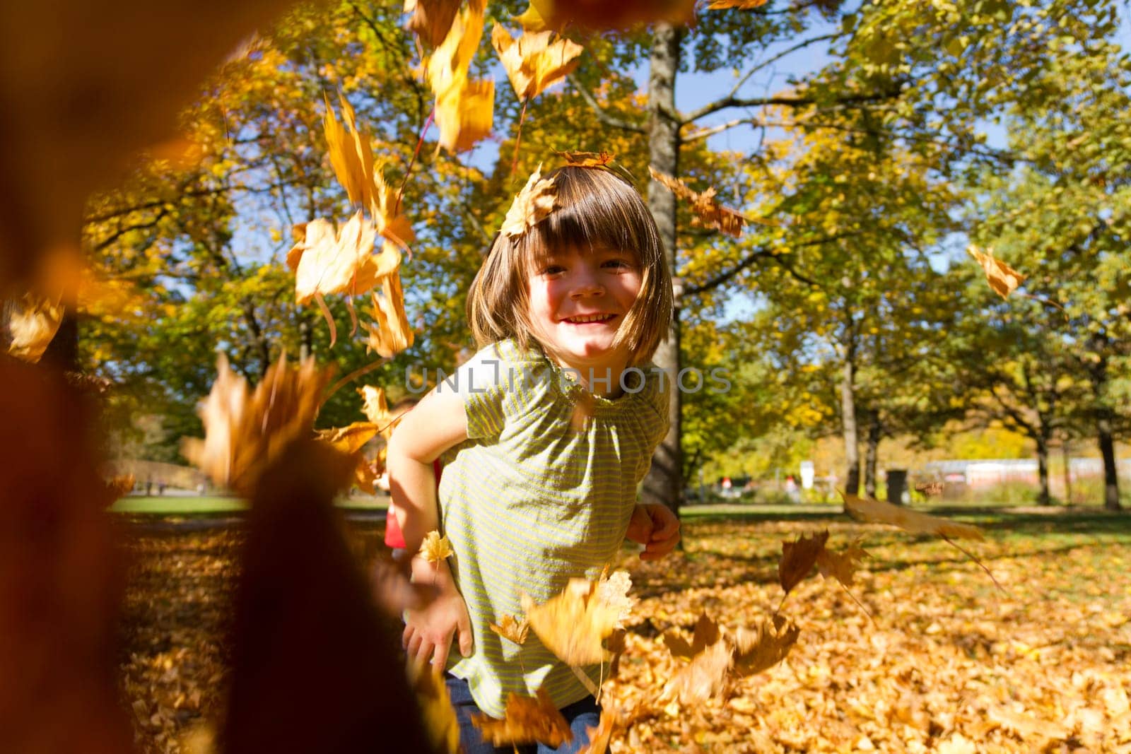 Girl playing outside with the colorful foliage in autumn