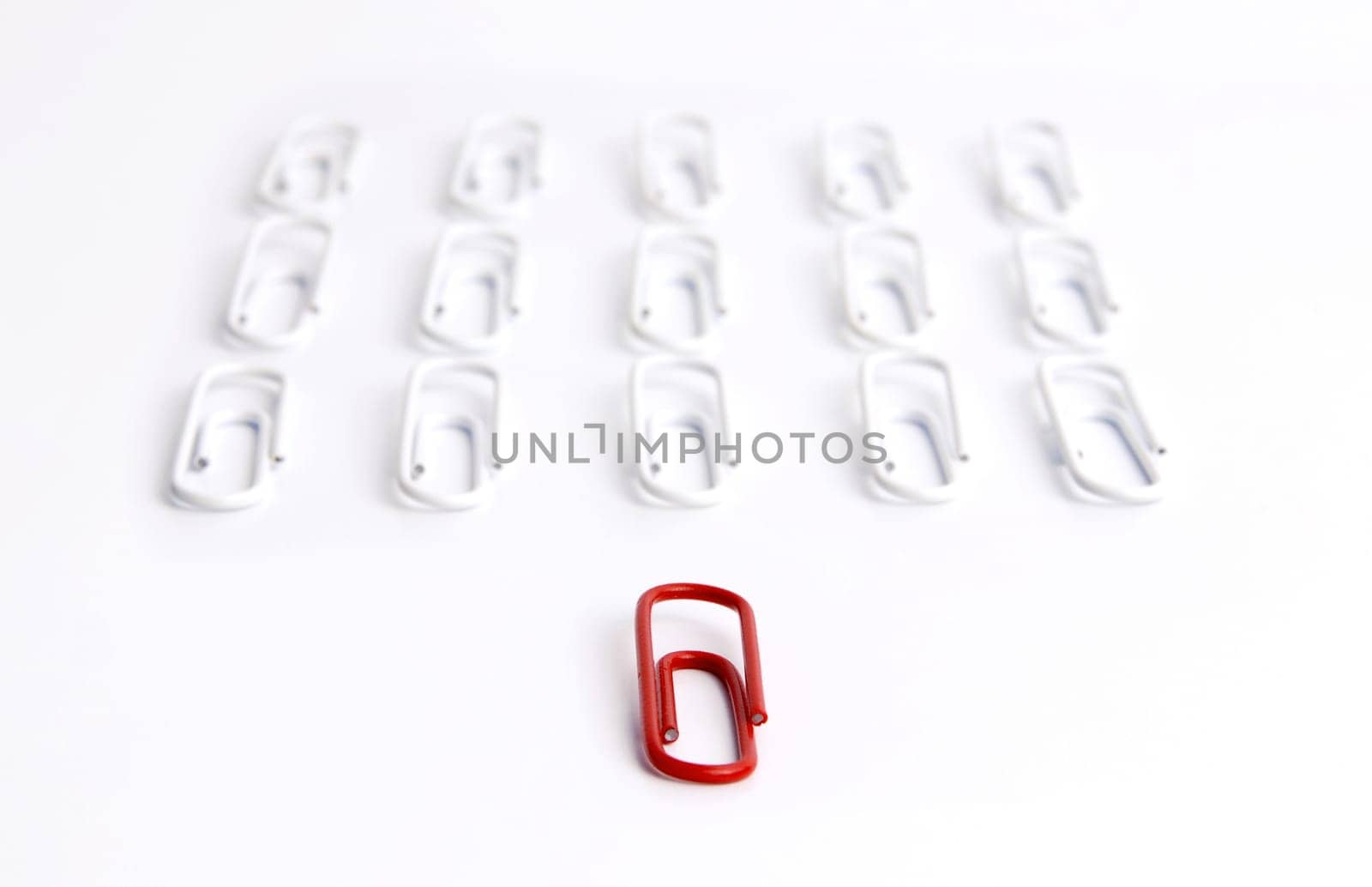 Conceptual idea of leadership. Red clip in focus, leading a group of aligned white clips