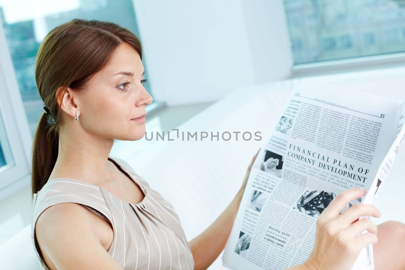 Attractive business lady with a newspaper being absorbed in her thoughts