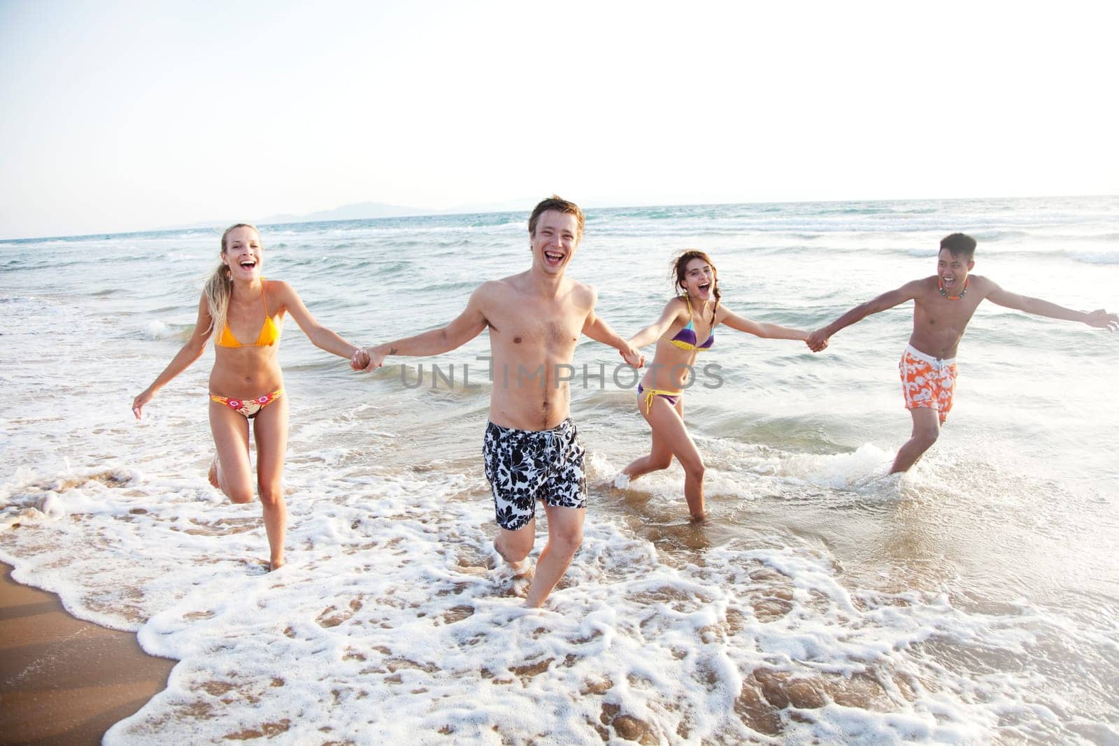 group of young people having fun, running in the surf