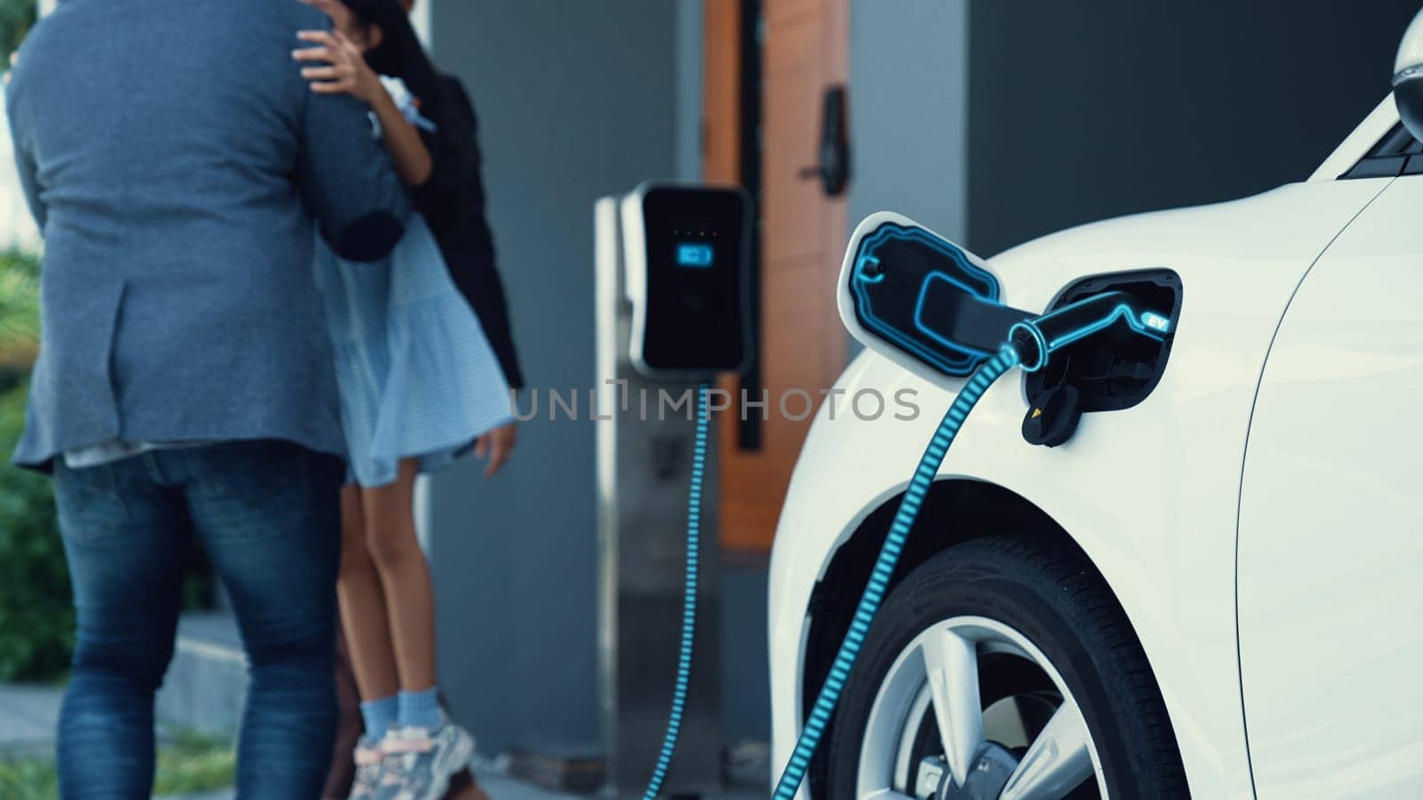 Modern family with young girl recharge electric car, EV charger from home charging station plugged in EV car in house garage. Smart and futuristic home energy infrastructure. Peruse