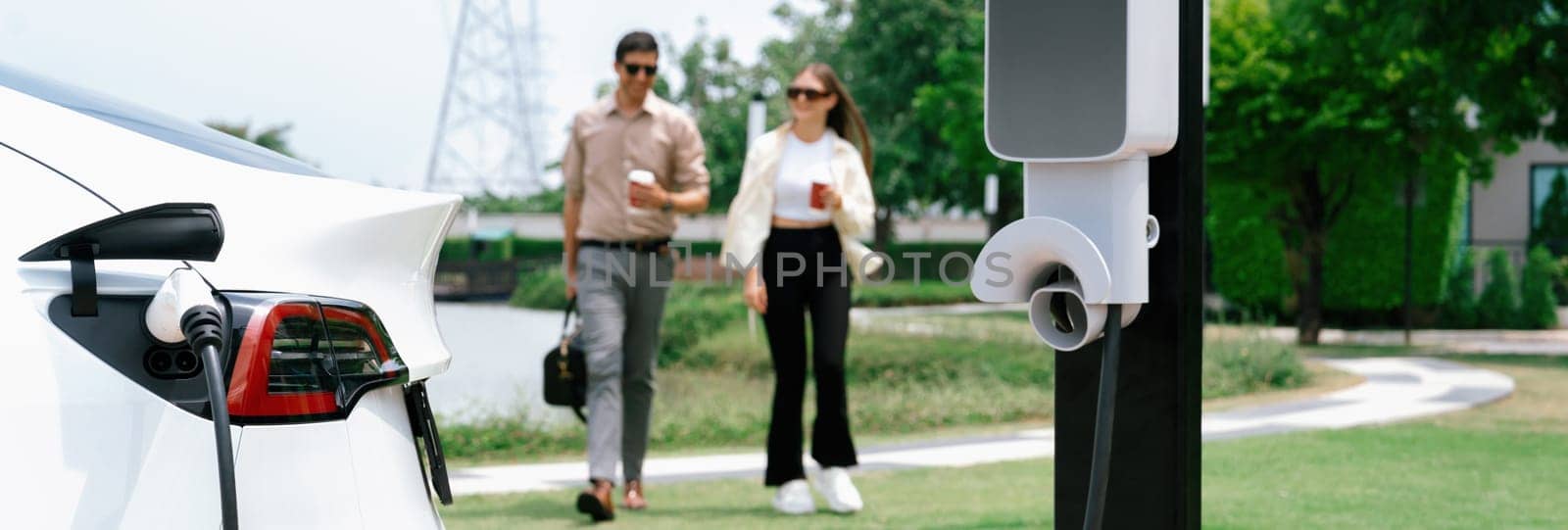 Young couple recharge EV car battery at charging station. Expedient by biancoblue