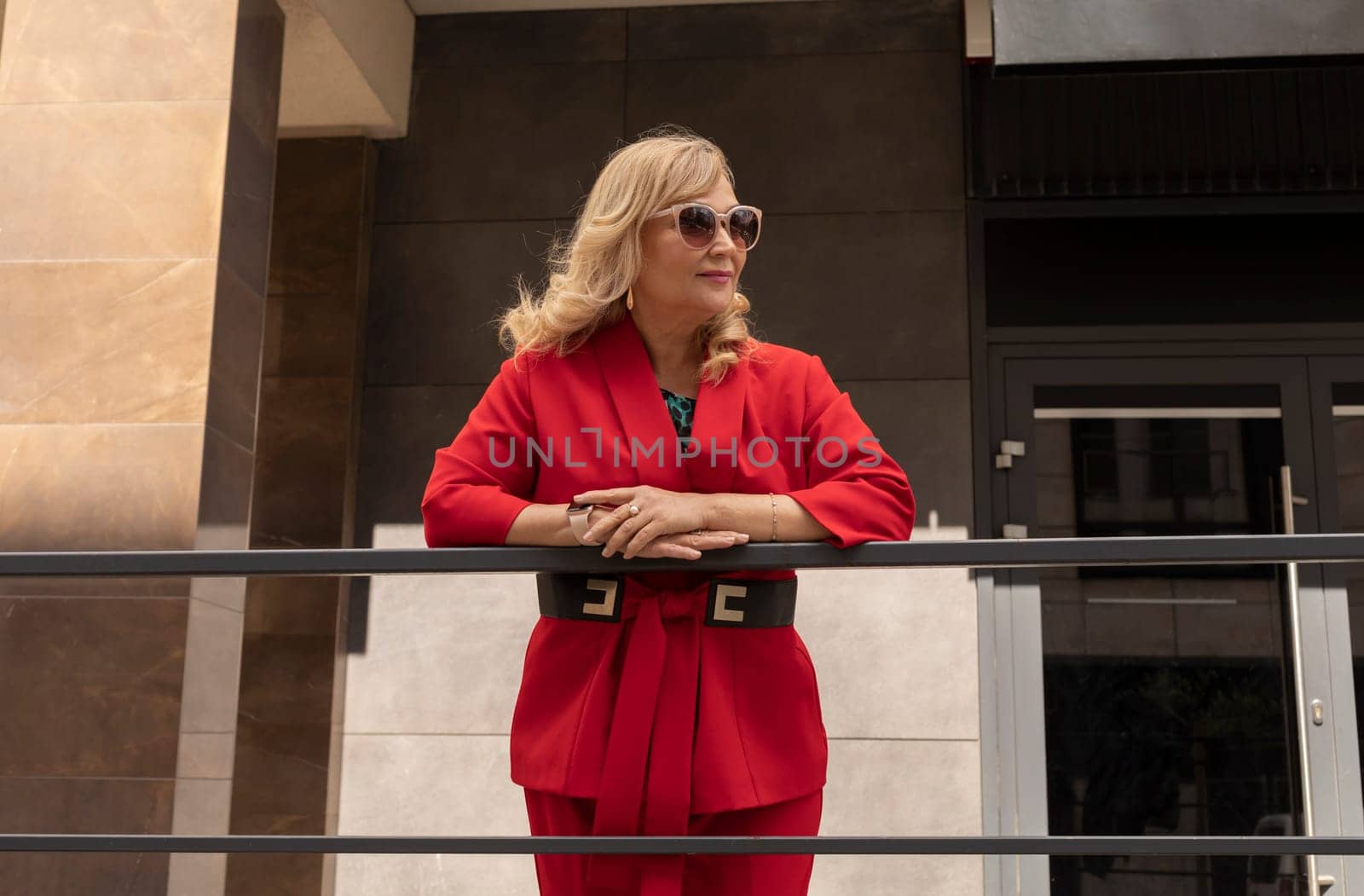 Portrait Attractive Elegant Mature Woman in her 60s, Modern Building on Background. Sexagenarian Female Outdoor in Summer Time, in City. Stylish Confident Senior Female With Sunglasses. Horizontal.