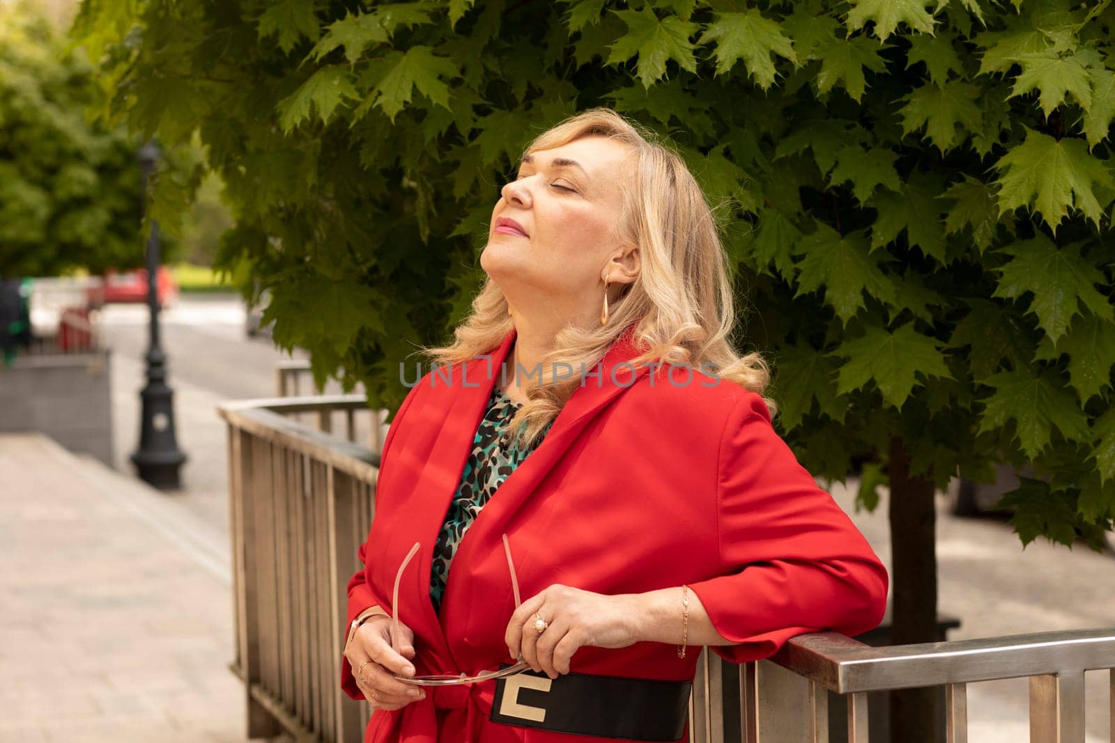 Portrait Relaxed Attractive Business Lady, Mature Sexagenarian Woman with Closed Eyes Outdoor. Stylish Senior Female in her 60s Holds Sunglasses. Boss or Manager Meditates. Horizontal Plane.