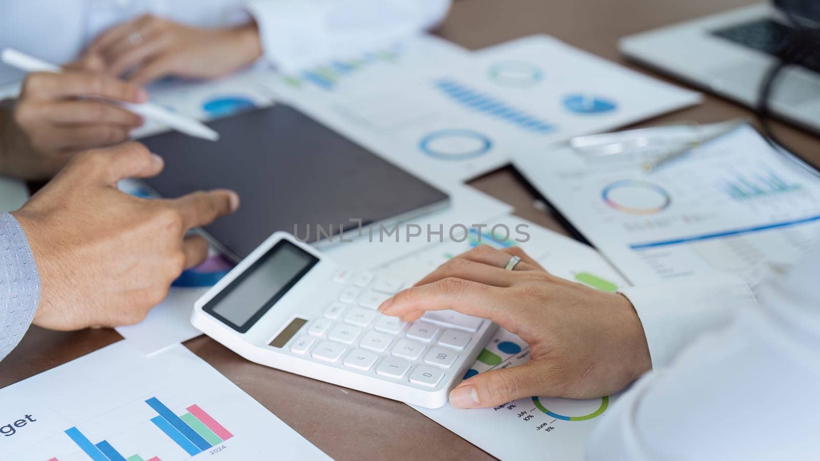 Businesswoman using a calculator to calculate numbers on a company's financial documents, she is analyzing historical financial data to plan how to grow the company. Financial concept.