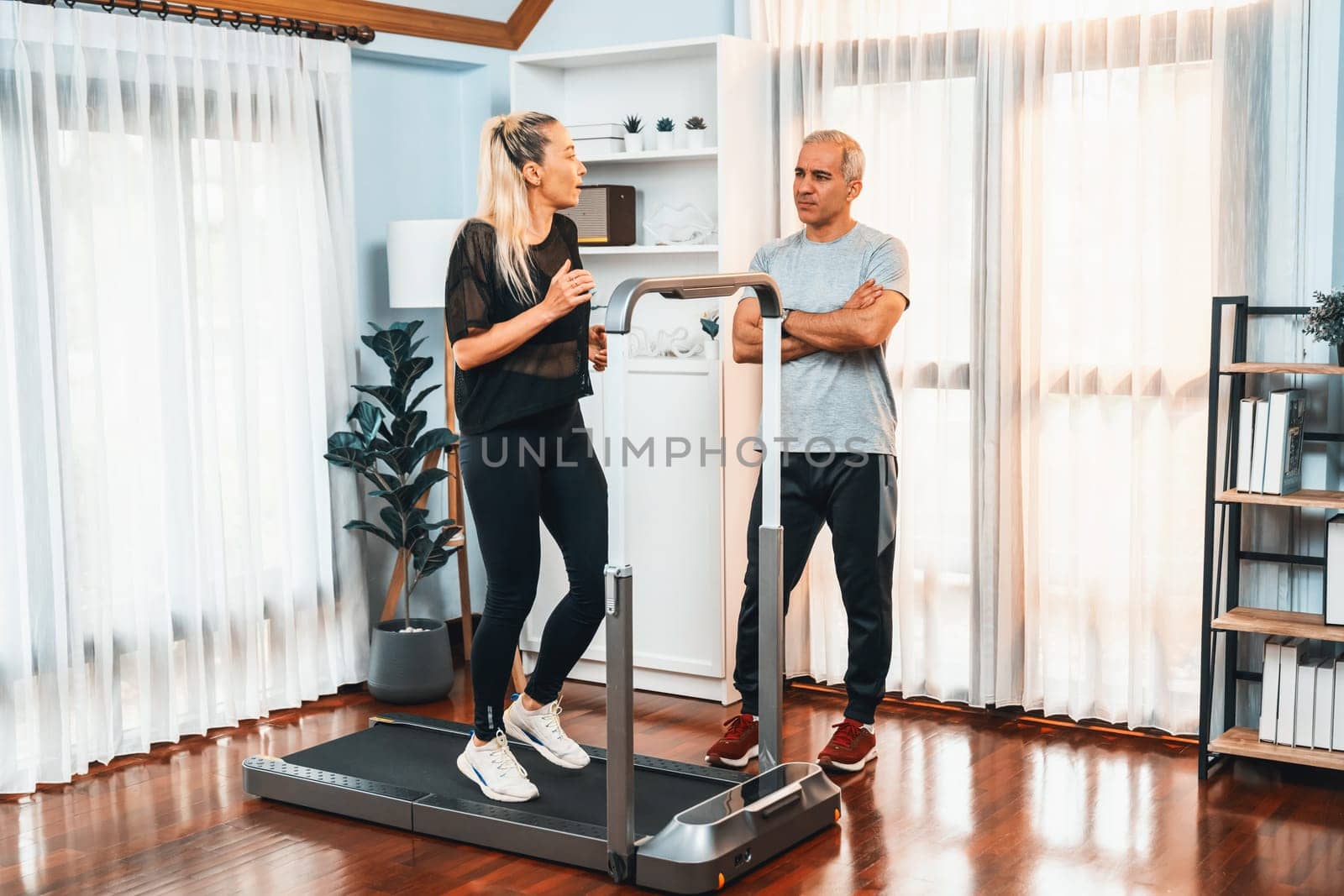 Active senior couple running on tread running machine at home together in full body shot as fitness healthy lifestyle and body care after retirement for pensioner. Clout