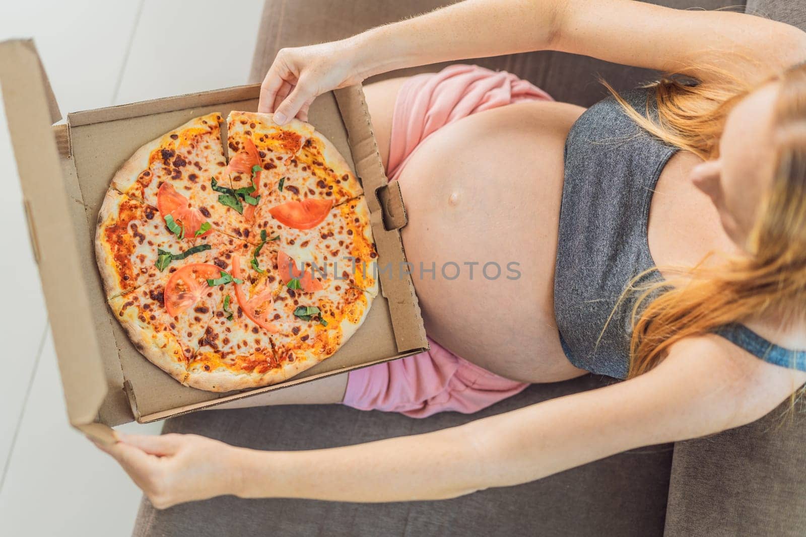 A pregnant woman enjoys a slice of pizza, savoring a moment of indulgence while satisfying her craving for a delightful, comforting treat. Excited Pregnant Young Lady Enjoying Pizza Holding Biting Tasty Slice Posing With Carton Box. Junk Food Lover Eating Italian Pizza. Unhealthy Nutrition Cheat Meal.