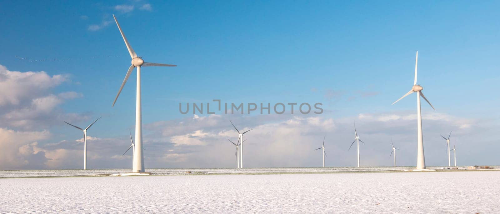 Windmill turbines n the Netherlands during winter with snow at the meadow field, windmill park during winter weather