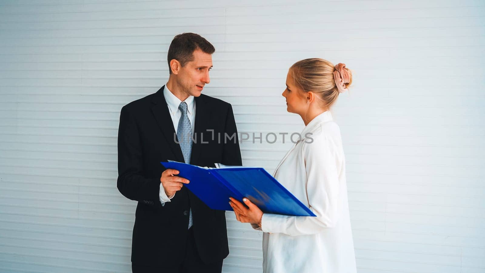 Two business people talk project strategy at office meeting room. Businessman discuss project planning with colleague at modern workplace while having conversation and advice on financial report. Jivy