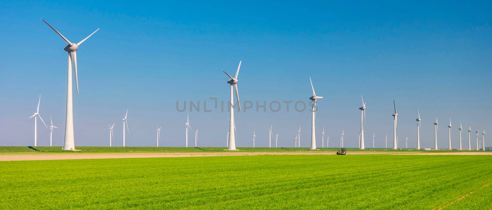 Windmill turbines with a green meadow field, huge windmill park in the Netherlands at the Noordoostpolder in Flevoland