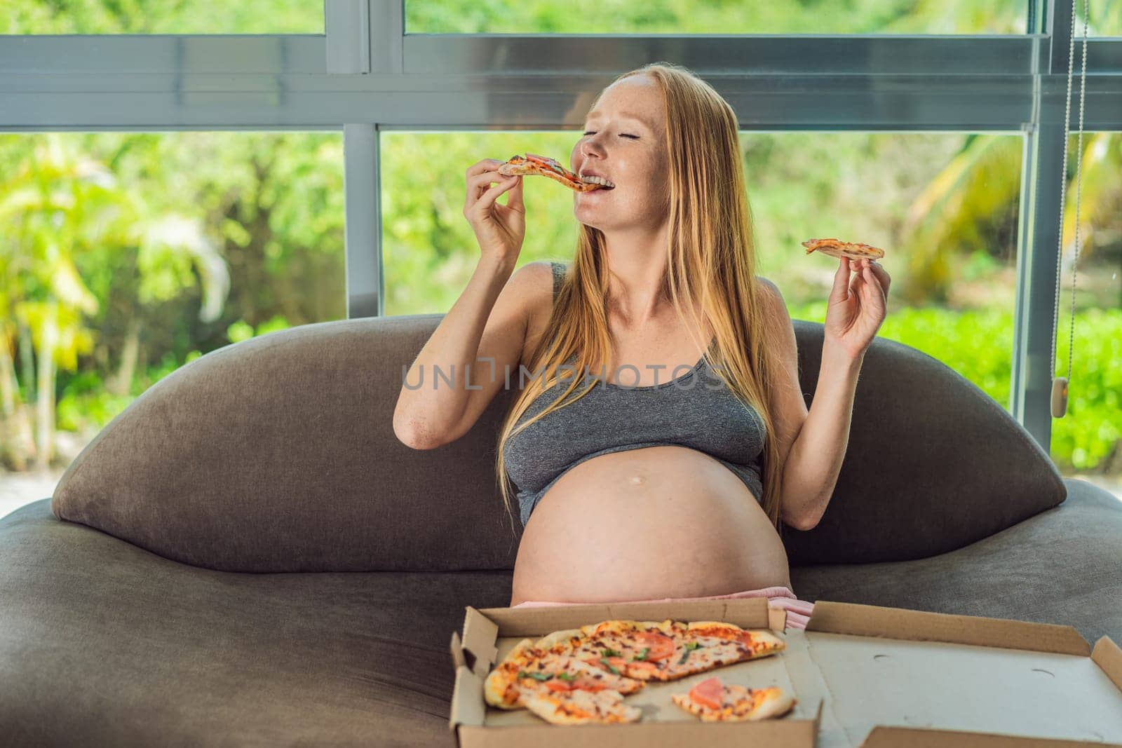 A pregnant woman enjoys a slice of pizza, savoring a moment of indulgence while satisfying her craving for a delightful, comforting treat. Excited Pregnant Young Lady Enjoying Pizza Holding Biting Tasty Slice Posing With Carton Box. Junk Food Lover Eating Italian Pizza. Unhealthy Nutrition Cheat Meal by galitskaya