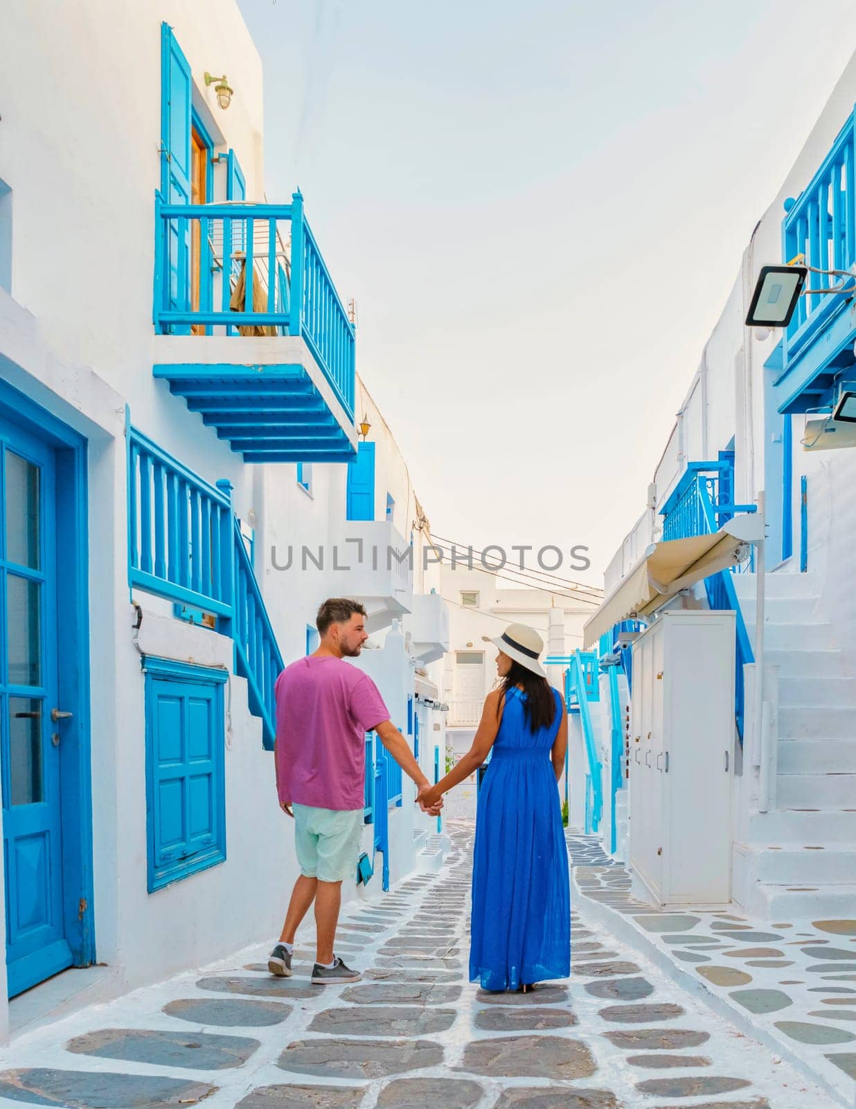 Romantic couple of men and women at the street of Mykonos Greek village in Greece by fokkebok