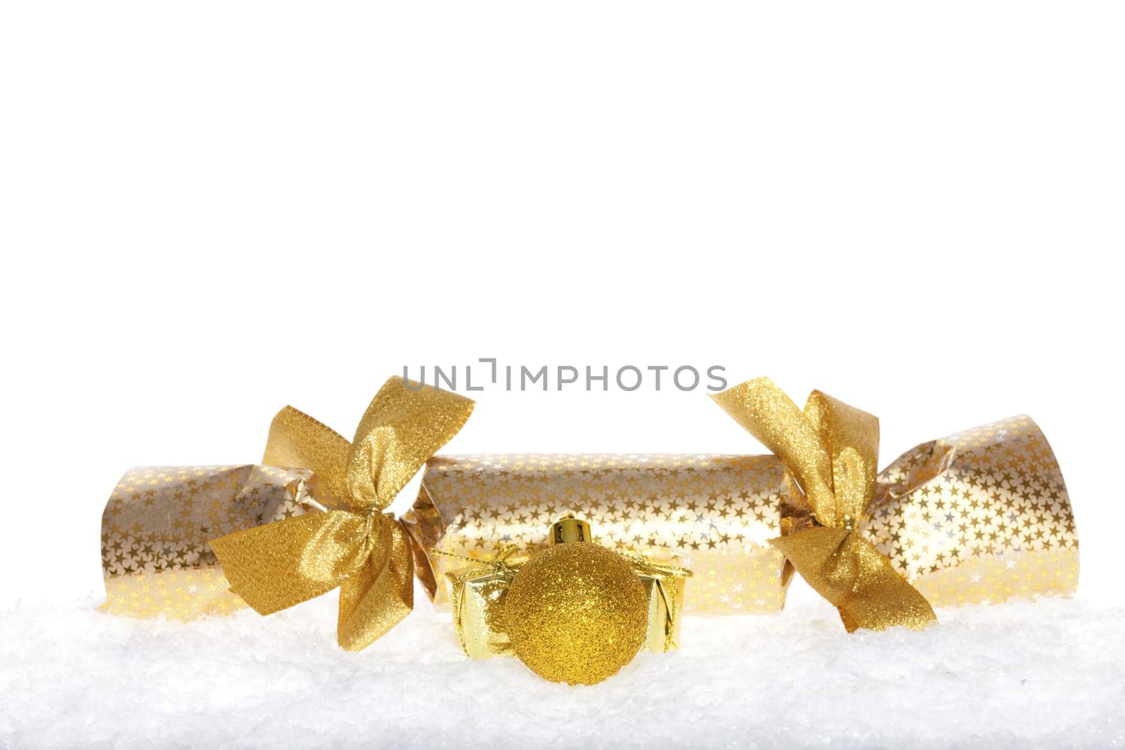 Christmas surprise with bows and golden ball lying in the snow against white background
