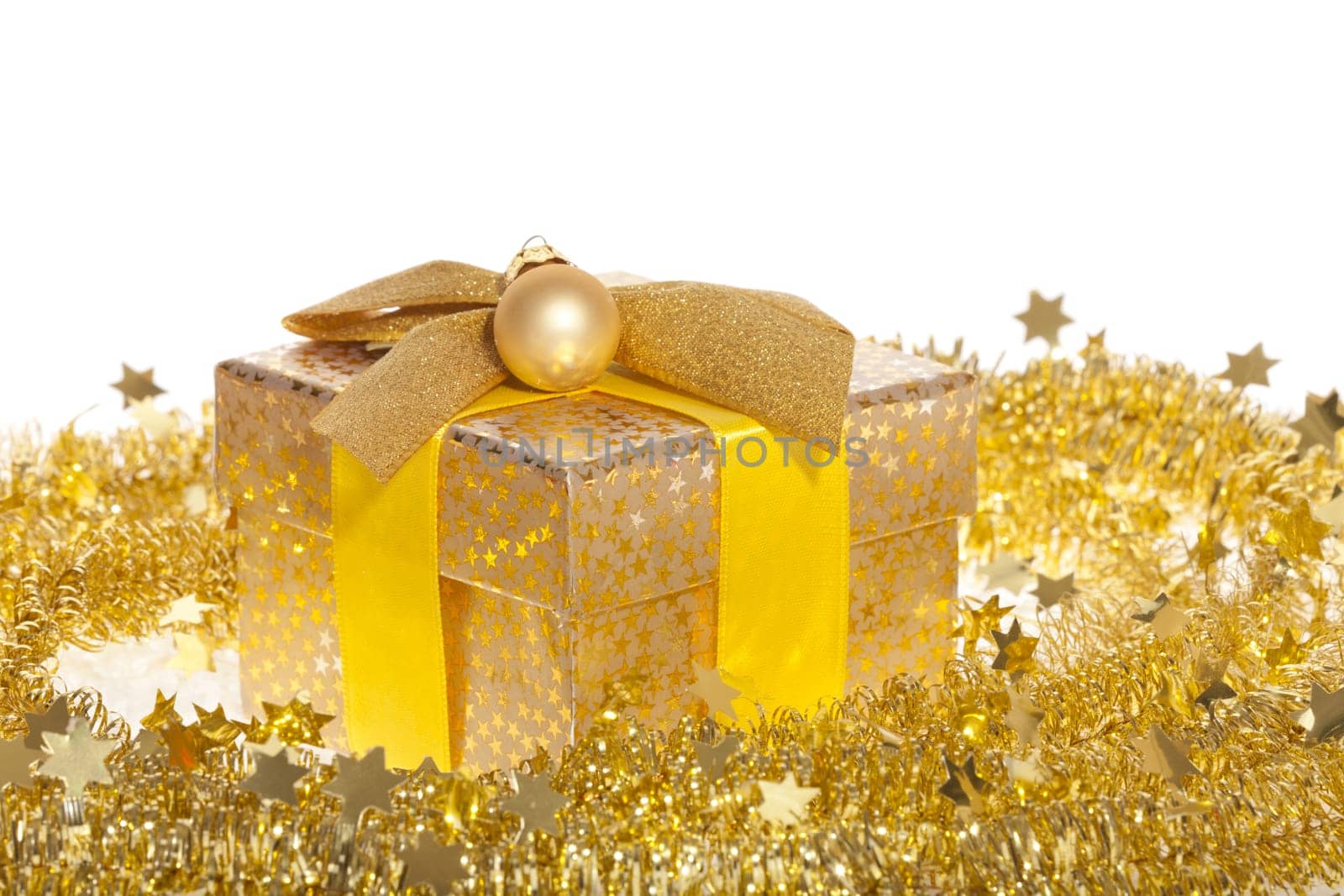 Package with bow and golden ball lying in the snow against white background