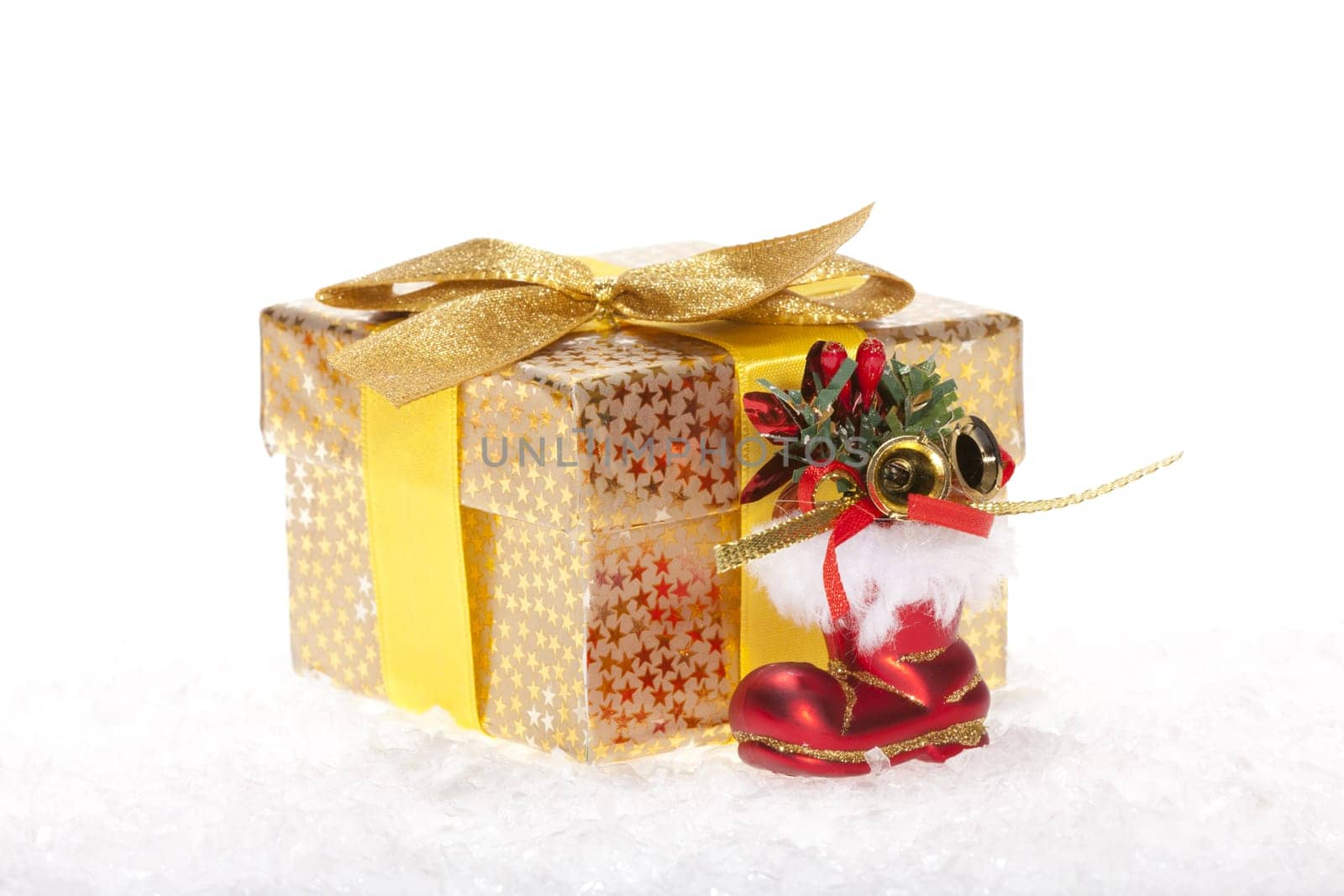 Package with bow,red Santa boots lying in the snow against white background