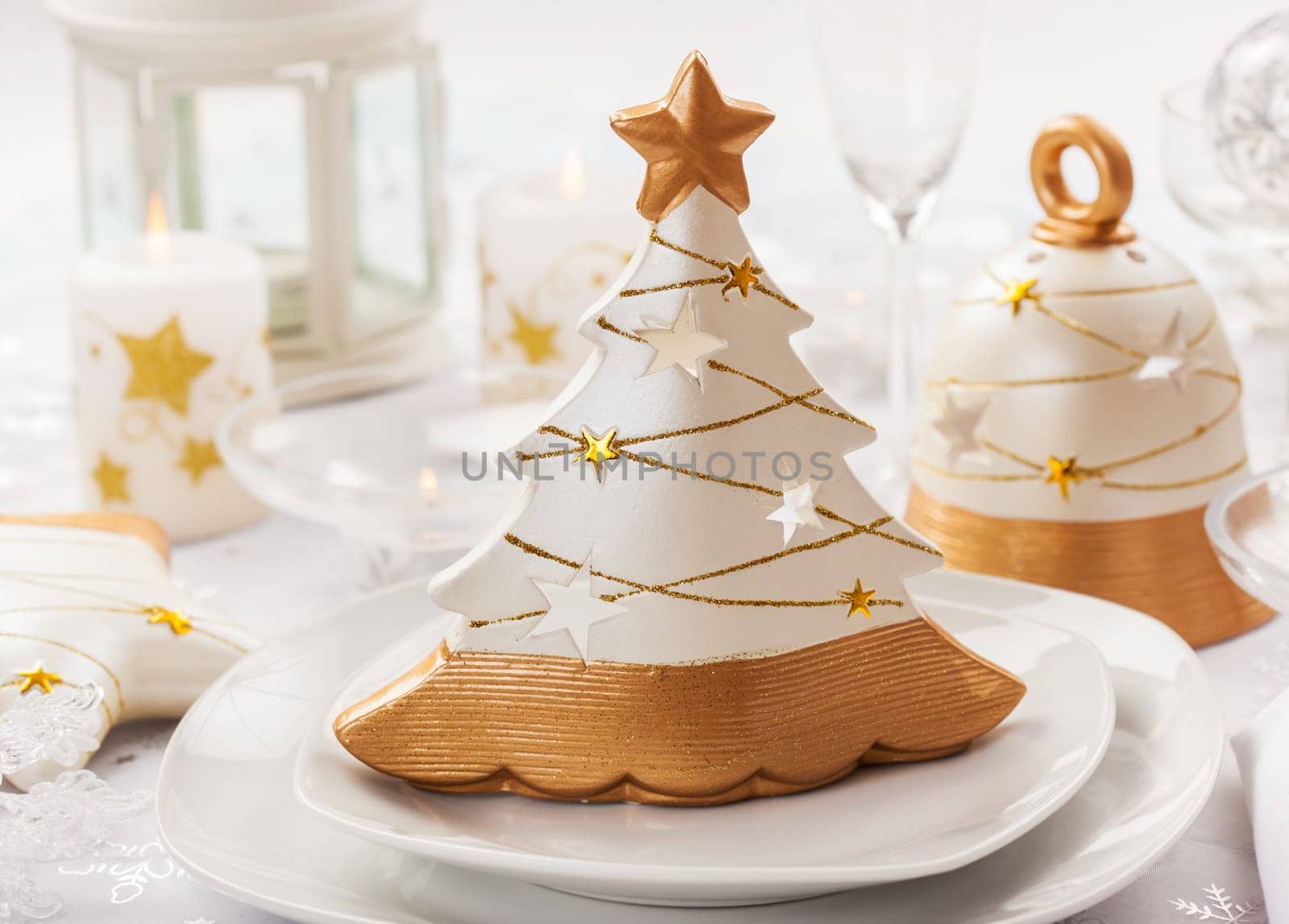 Festive table for Christmas with small tree in white and golden tones