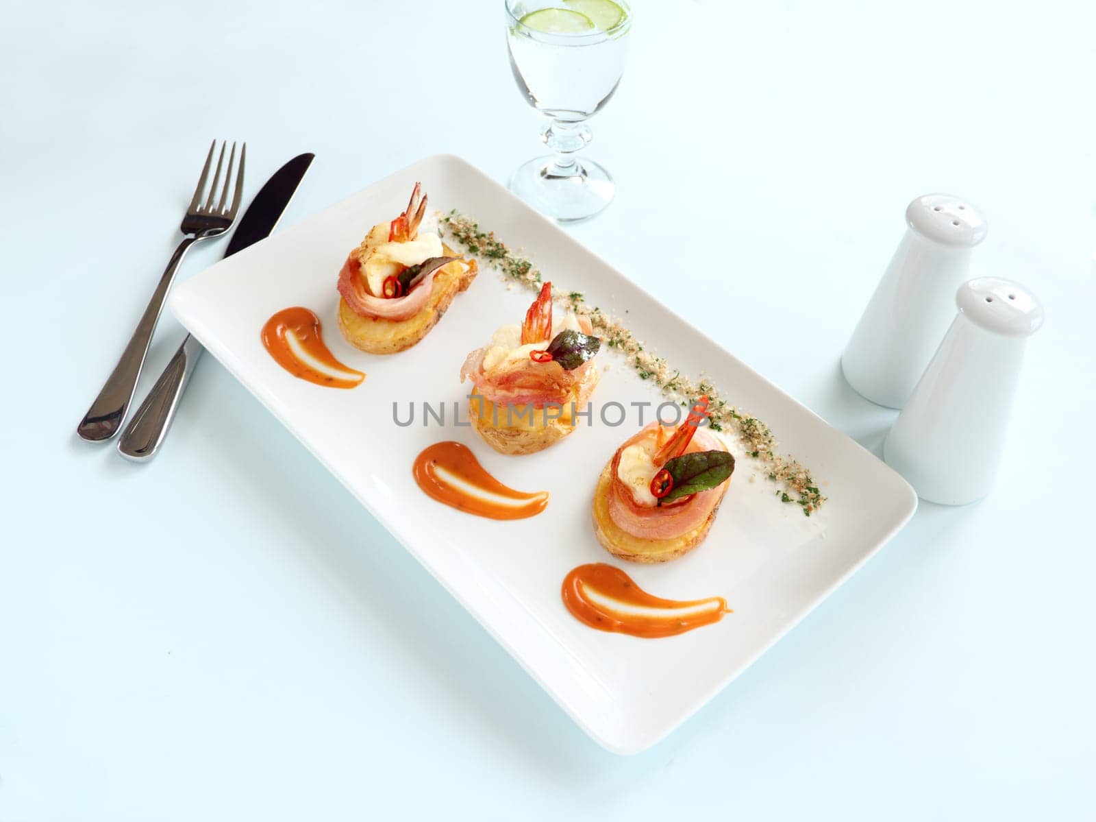 Delicious and delicate shrimps wrapped in bacon on potato slices with a spinach leaf.