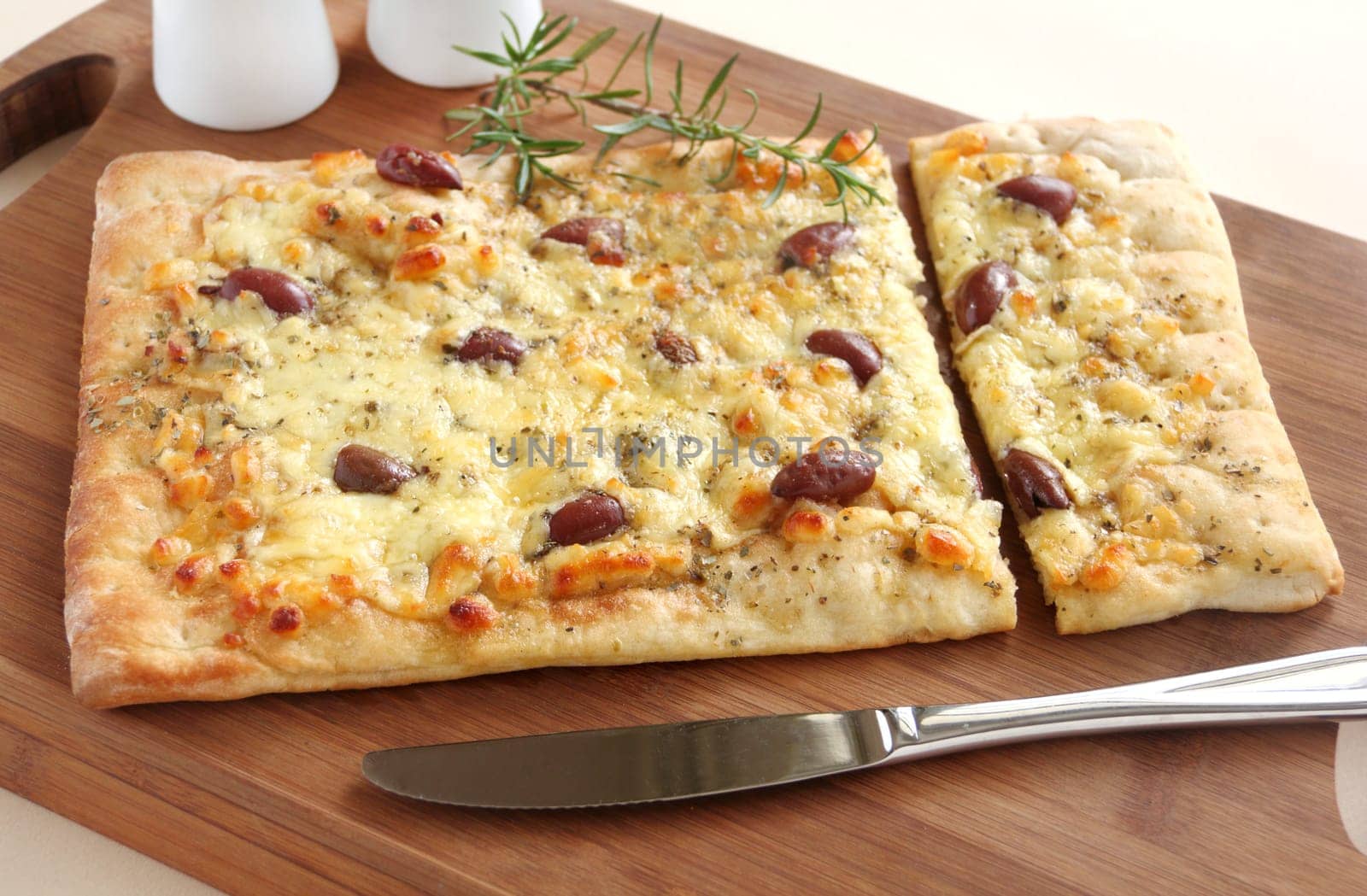 Rectangular gourmet pizza with cheese and olives ready to serve.