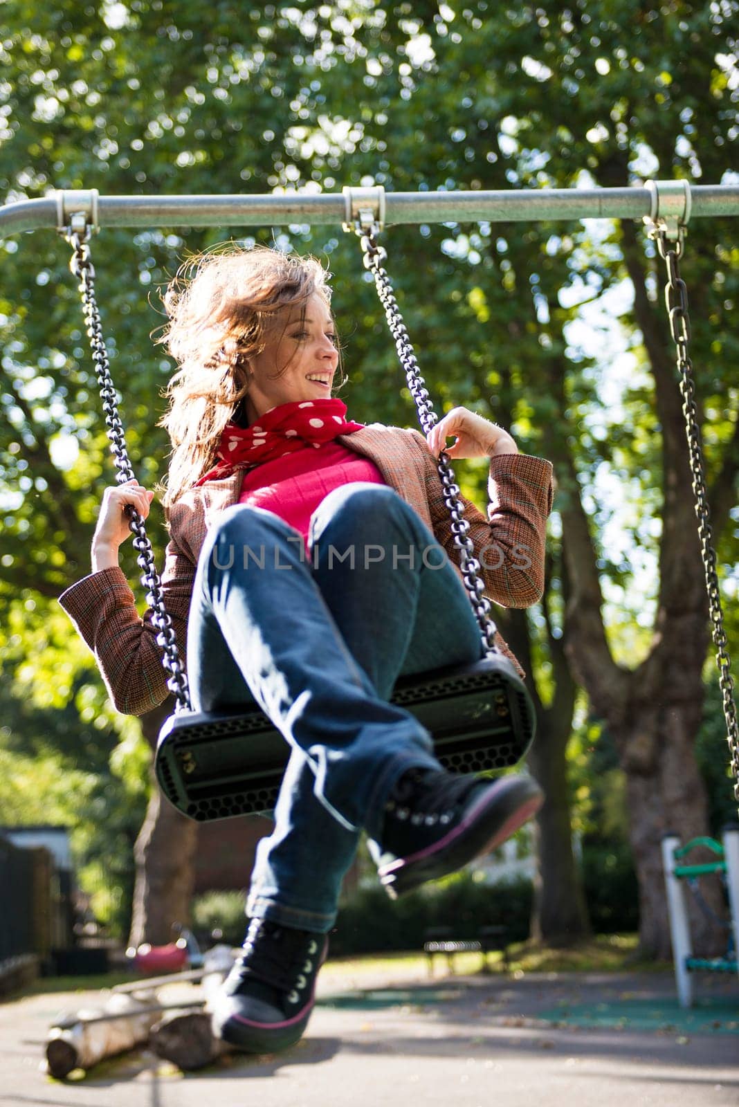 Low angle shot of beautiful young woman on swing in playground.
