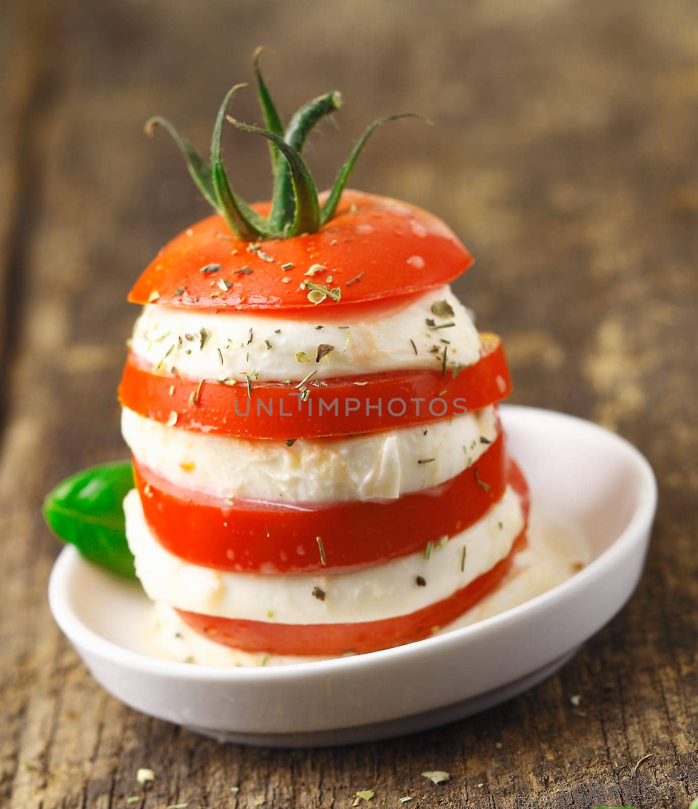 Tower of altenating slices of ripe red tomato and cheese served as a vegetarian acompaniment to a meal