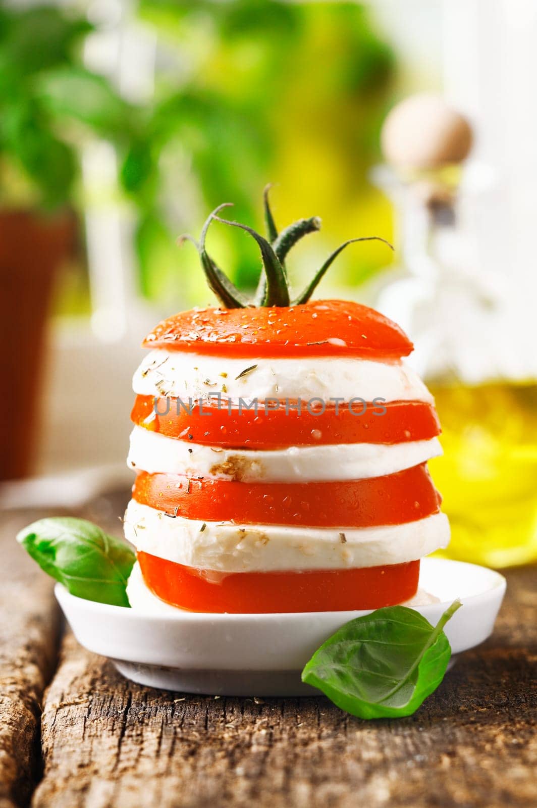Cheese and tomato tower with alternating slices of fresh ripe red tomato and cheese served on a rustic wooden table