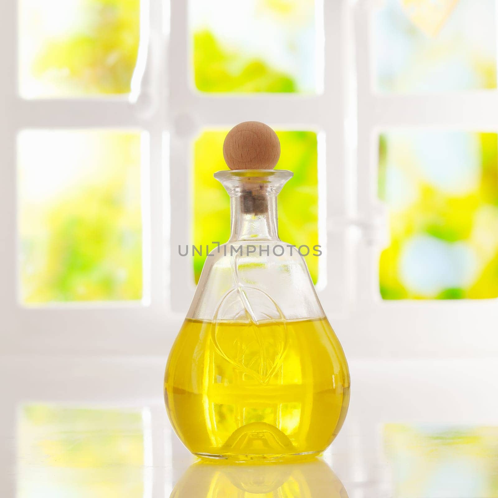 Glowing golden olive oil in a stoppered glass container for dispensing for cooking or as a salad dressing backlit by a bright airy window