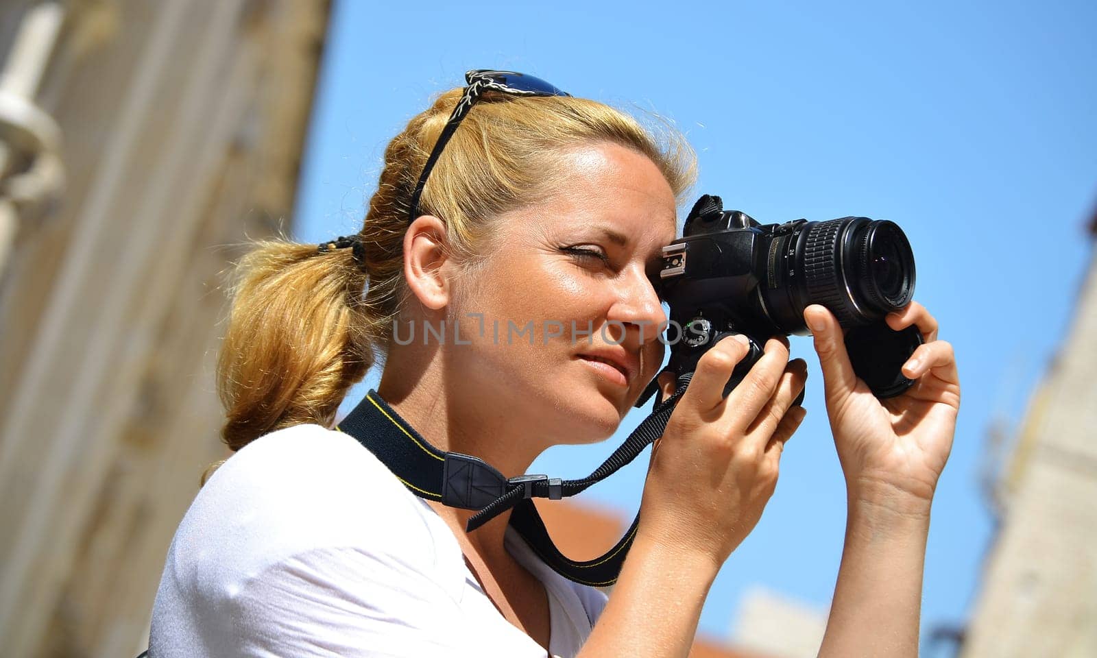 Young female tourist visiting Mediterranean old town on vacation. Woman taking photos on the street